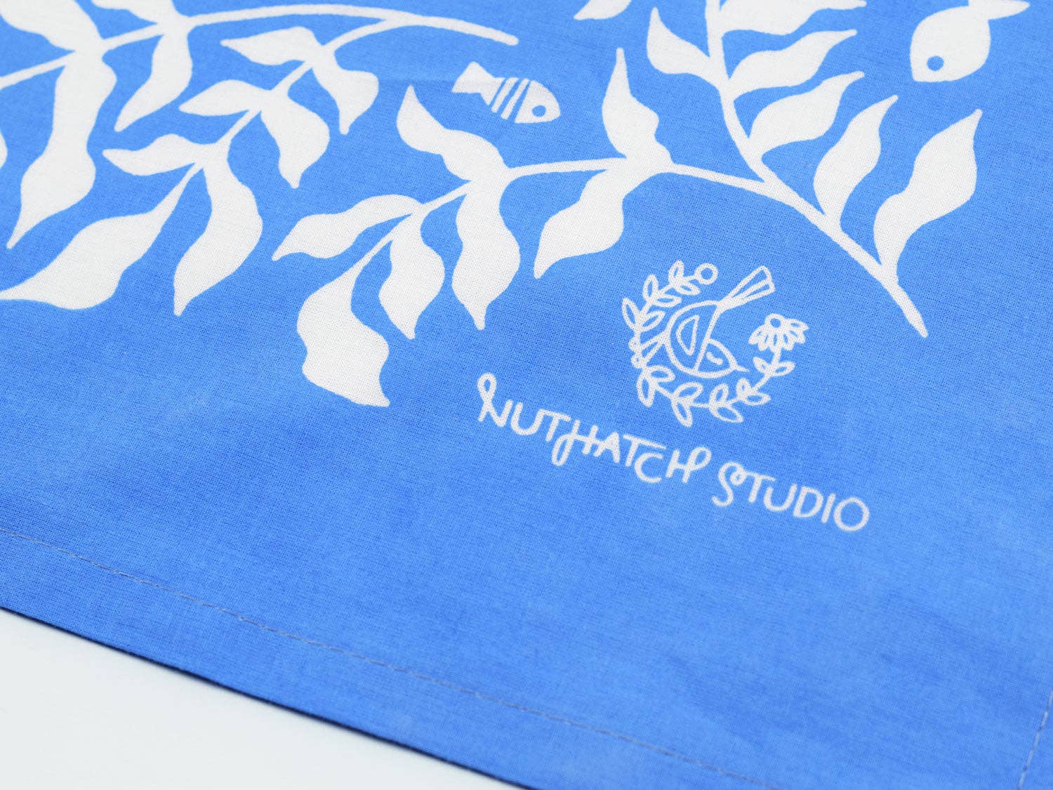 Close-up showing the signature and corner detail of the Cerulean Mermaid organic cotton bandana by Chrissie Van Hoever, featuring premium stitching and vibrant blue fabric available at Gray Man Gallery in Pawleys Island.