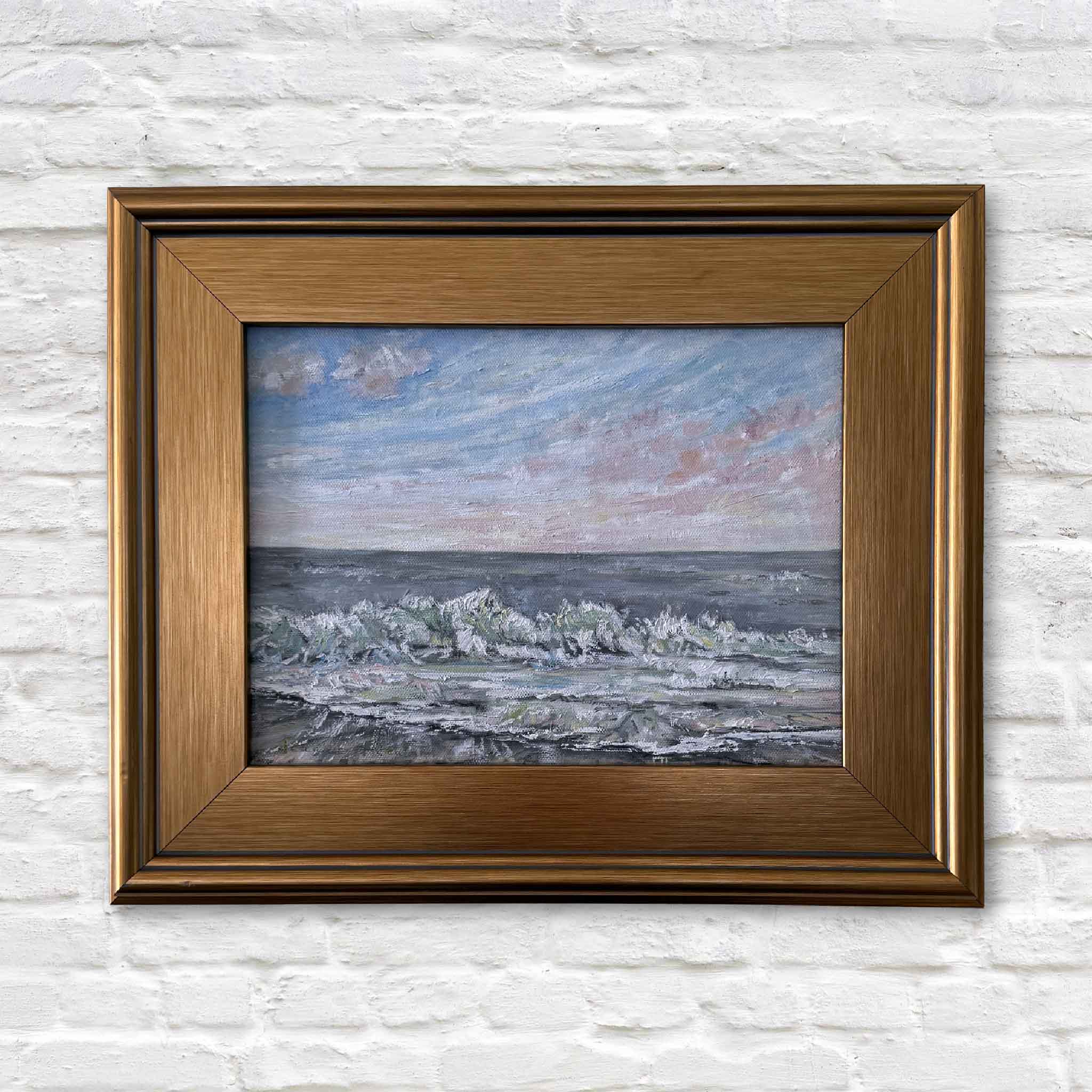 Framed original oil painting Coastal Calm by Jeanne O’Neal featuring soft ocean waves and pastel sky over the South Carolina shoreline, professionally framed in warm gold and displayed at Gray Man Gallery in Pawleys Island
