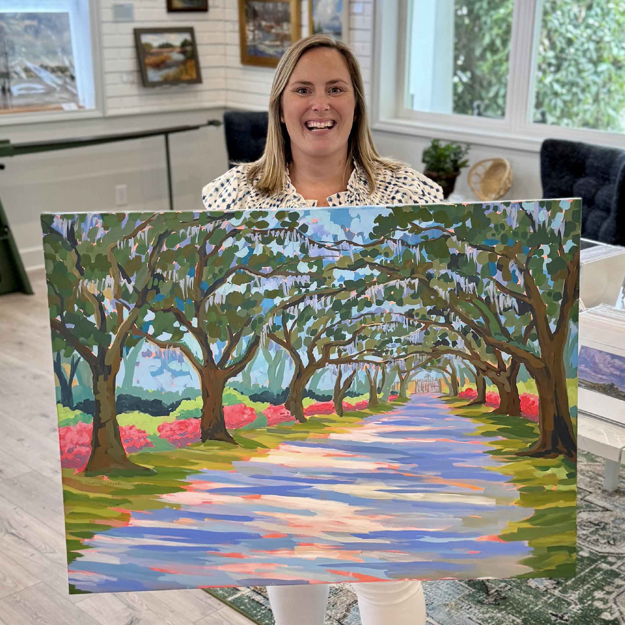 Bordy holding Azaleas in Litchfield acrylic painting by local artist Elizabeth Sheats inside Gray Man Gallery, showing scale of the gallery wrapped canvas featuring the Avenue of Oaks and vibrant azalea blooms