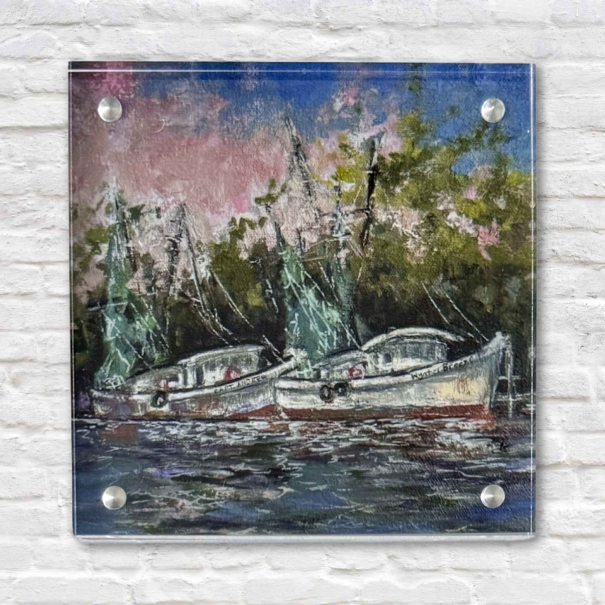 Acrylic block art print titled “Evening Light” by local artist Jeanne O’Neal, featuring shrimp boats resting at the dock beneath a pink and blue Lowcountry sky, shown straight-on to highlight the clear acrylic block, polished edges, and mounting hardware, photographed at Gray Man Gallery in Pawleys Island, South Carolina
