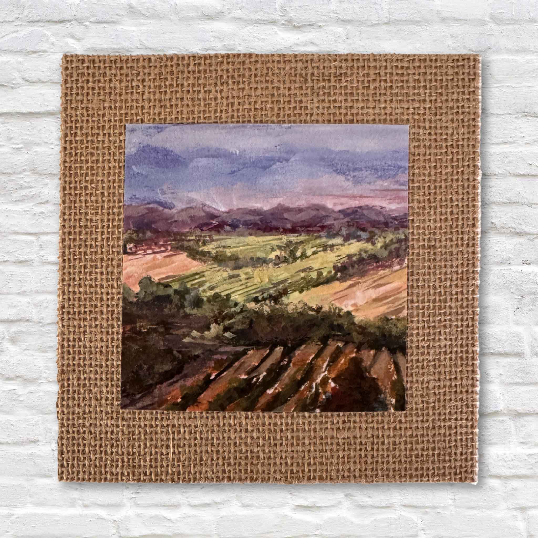 Primary product image of “Fields of France,” a 4x4 fine art print by Jeanne O’Neal, local South Carolina artist at Gray Man Gallery in Pawleys Island. The landscape features rolling countryside in lavender, green, and warm earth tones, mounted on textured burlap matboard for a rustic, ready-to-frame presentation.