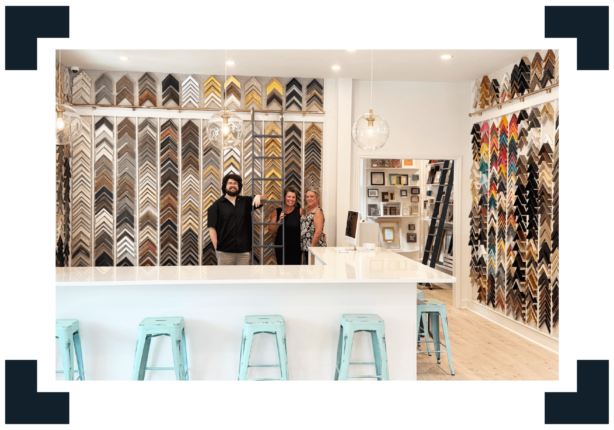 the gray man gallery team in front of a wall of frame samples