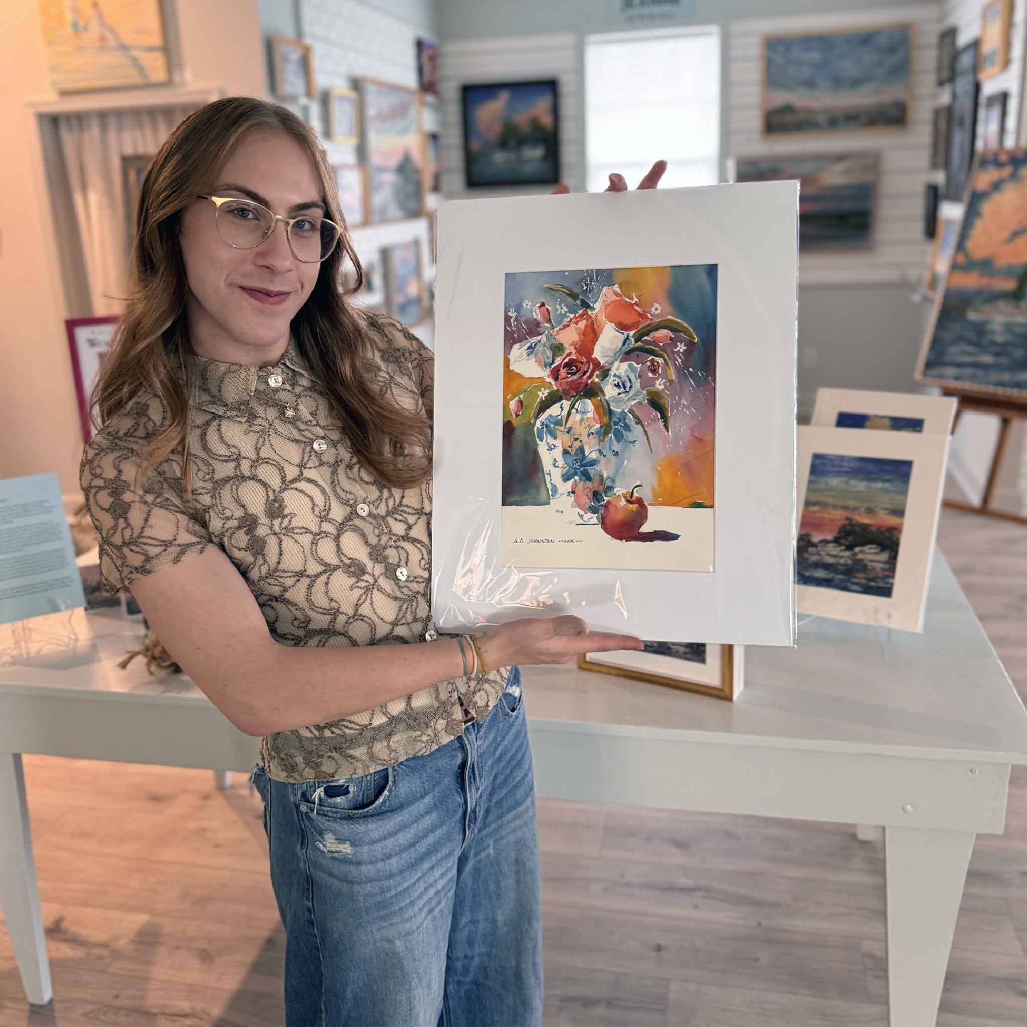 Alex holding “Blue Vase,” a colorful floral watercolor by Gary Johnston, matted to 16×20 inside Gray Man Gallery.
