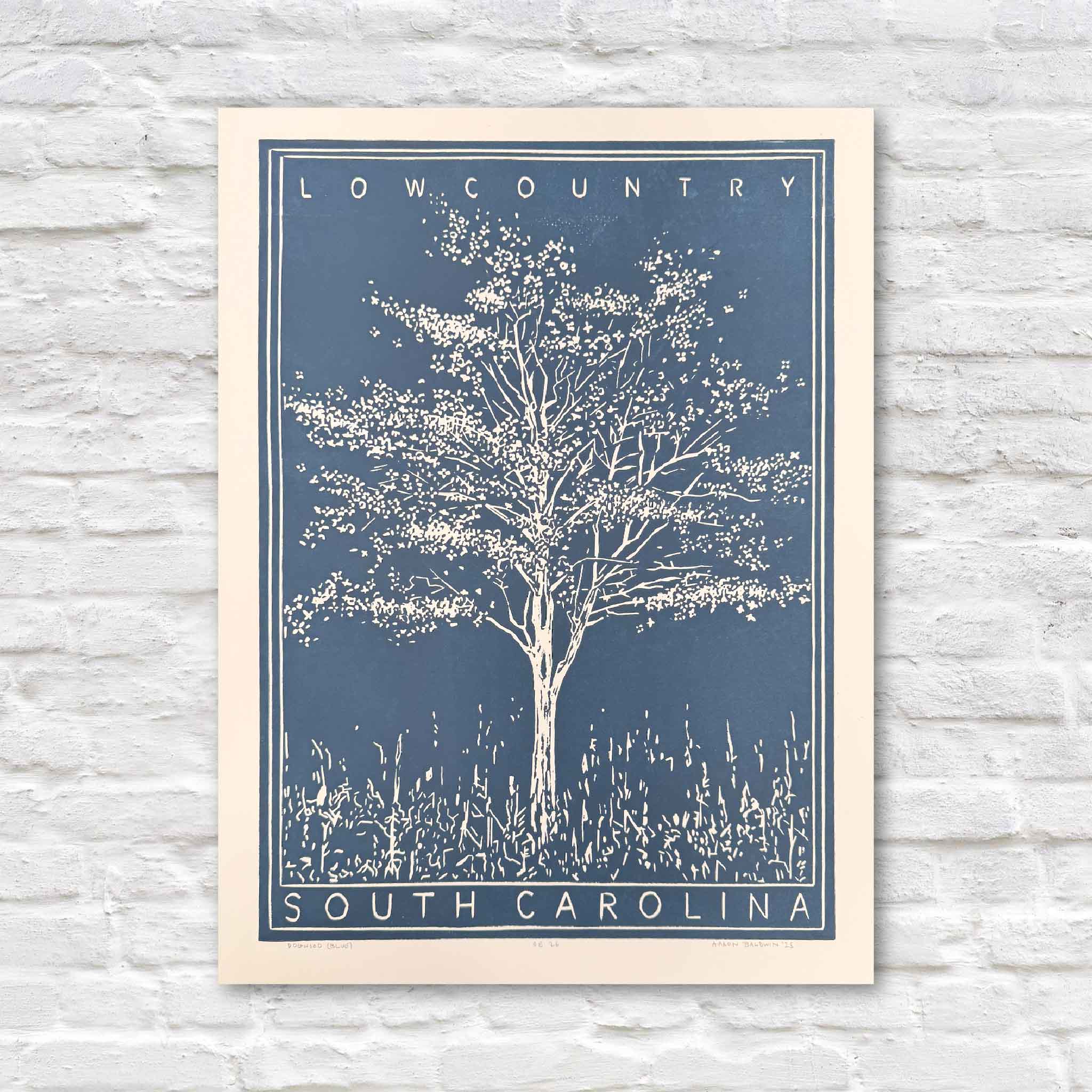 Aaron Baldwin’s Dogwood linocut in blue, featuring a blooming dogwood tree rendered in bold graphic lines inspired by the South Carolina Lowcountry.