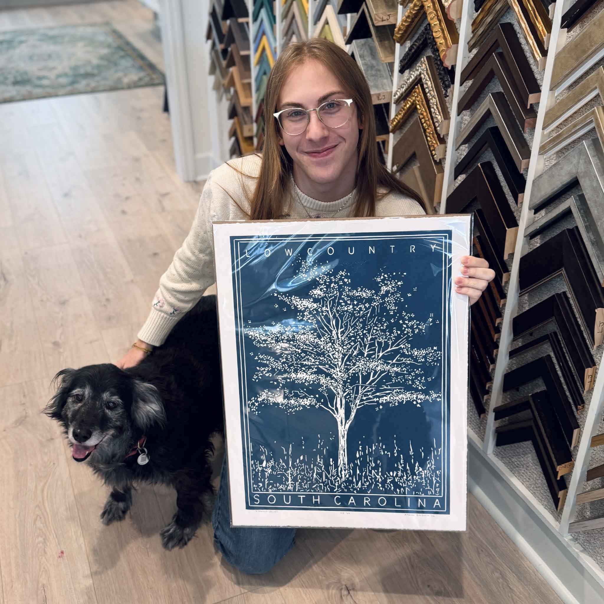 A Gray Man Gallery team member holding Aaron Baldwin’s Dogwood original linocut to show scale and detail in the gallery.
