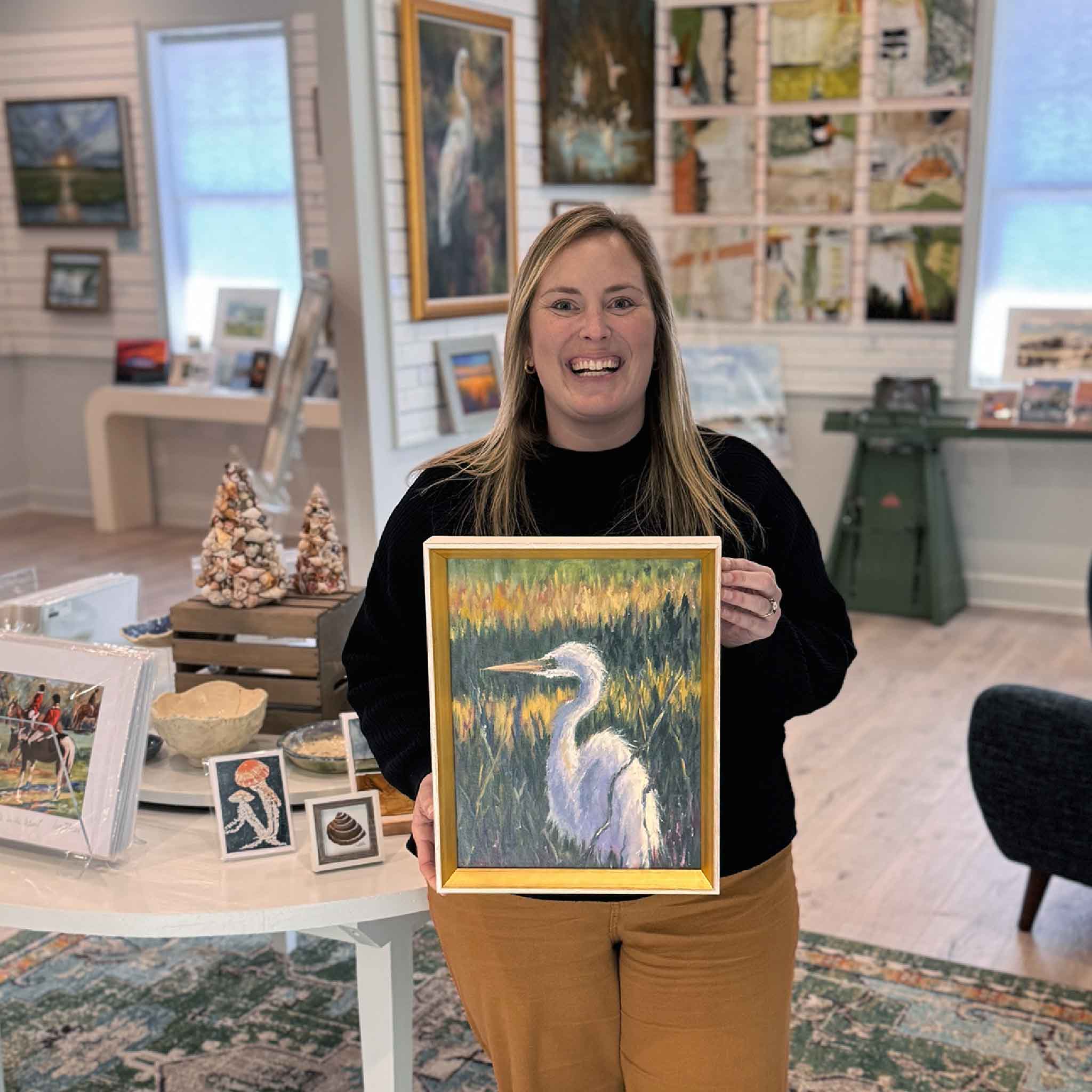 Bordy holding Marsh Sentinel, an original 11x14 oil painting by local artist Jeanne O’Neal at Gray Man Gallery in Pawleys Island, featuring a white egret in a Lowcountry marsh landscape