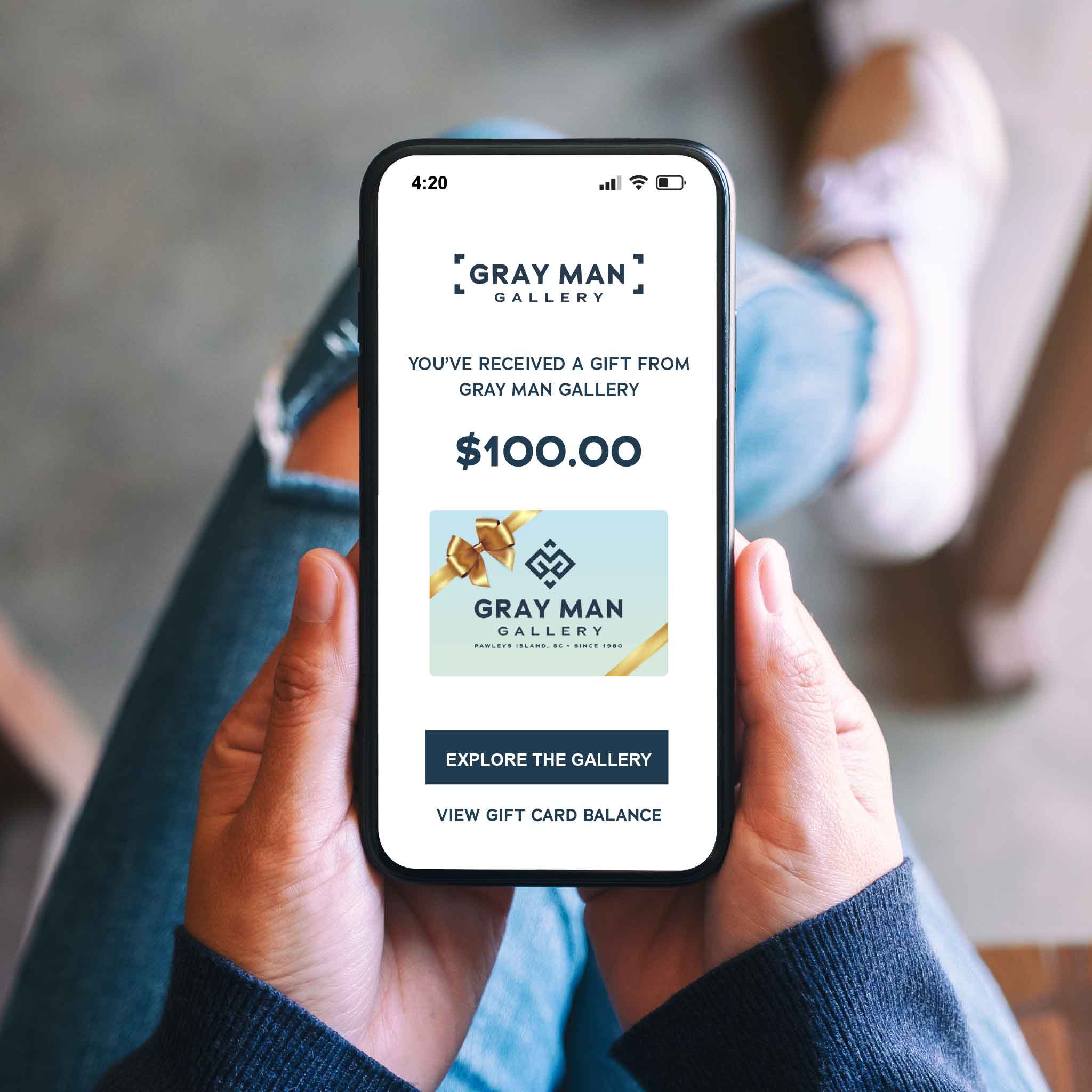Lifestyle image of a Gray Man Gallery digital gift card email displayed on a smartphone, highlighting instant delivery and online redemption for local art, custom framing, and curated coastal gifts from the Pawleys Island, South Carolina gallery.