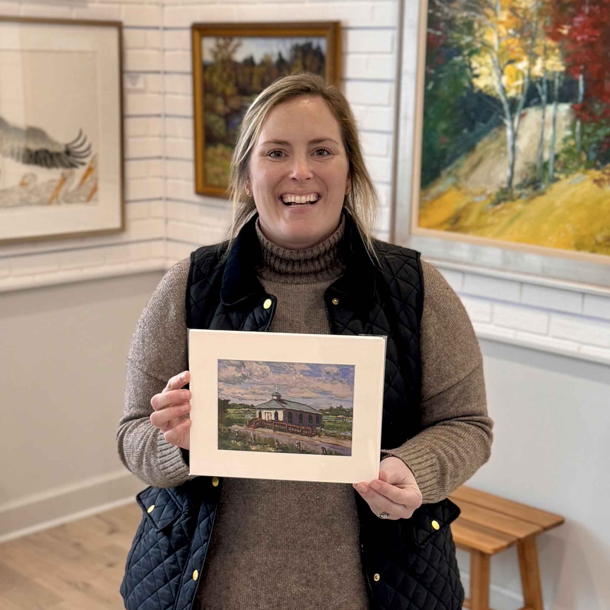 Bordy holding “Quiet After the Storm” fine art print by local Lowcountry artist Jamie Arnold inside Gray Man Gallery in Pawleys Island, South Carolina, showcasing coastal marsh sunset artwork and custom framing