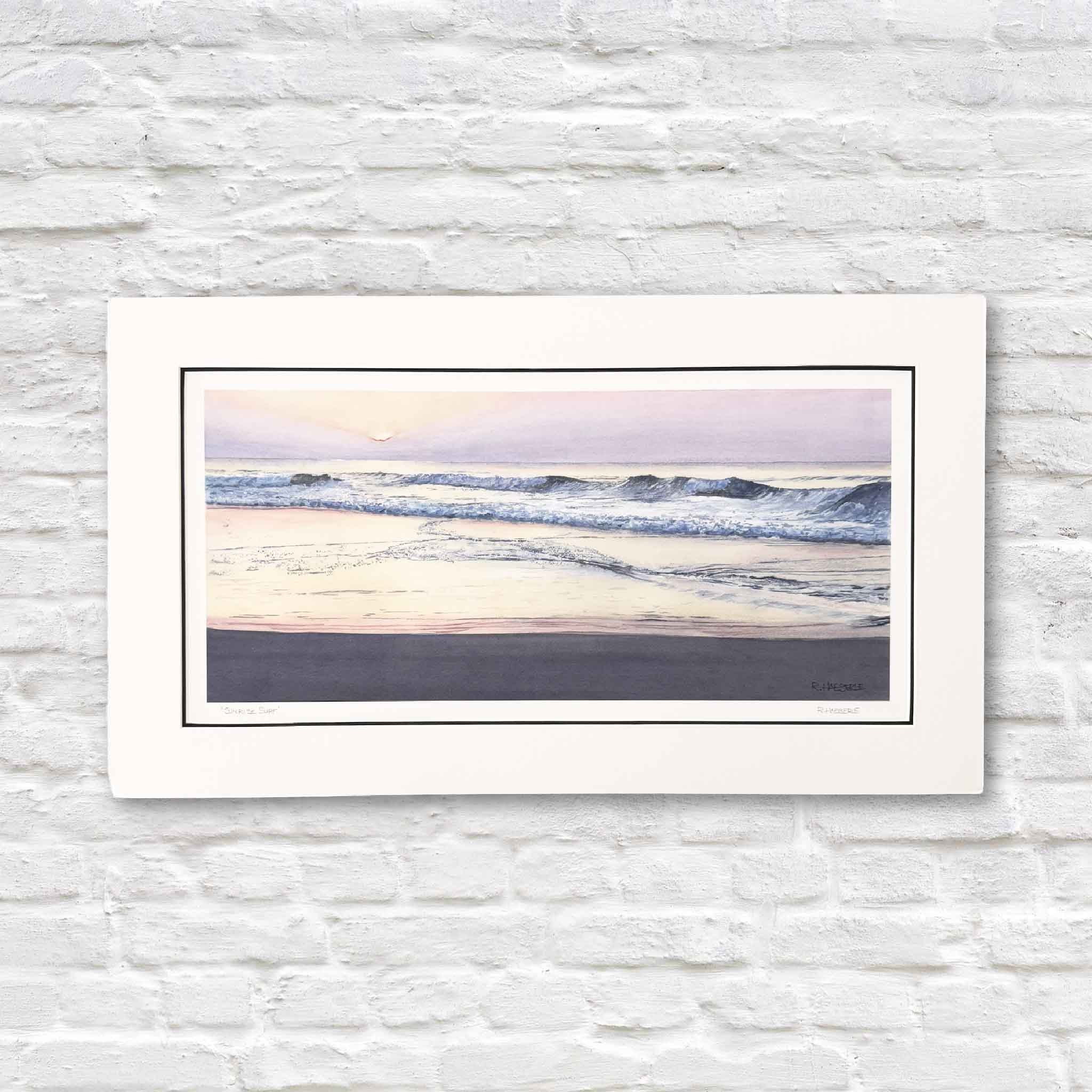 Sunrise Surf by Ron Haeberle, a panoramic coastal art print featuring soft pastel sunrise colors and gentle ocean waves, double matted and sized 28x16 inches, available at Gray Man Gallery.