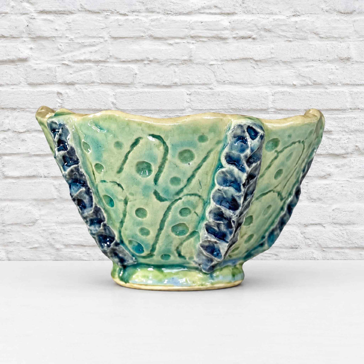 Handmade Tidepool Texture Bowl by Pawleys Island artist and Gray Man Gallery founder Vida Miller, featuring a sculptural seafoam green ceramic exterior with organic impressions, raised deep blue details and a softly irregular rim inspired by coastal textures of the South Carolina Lowcountry.