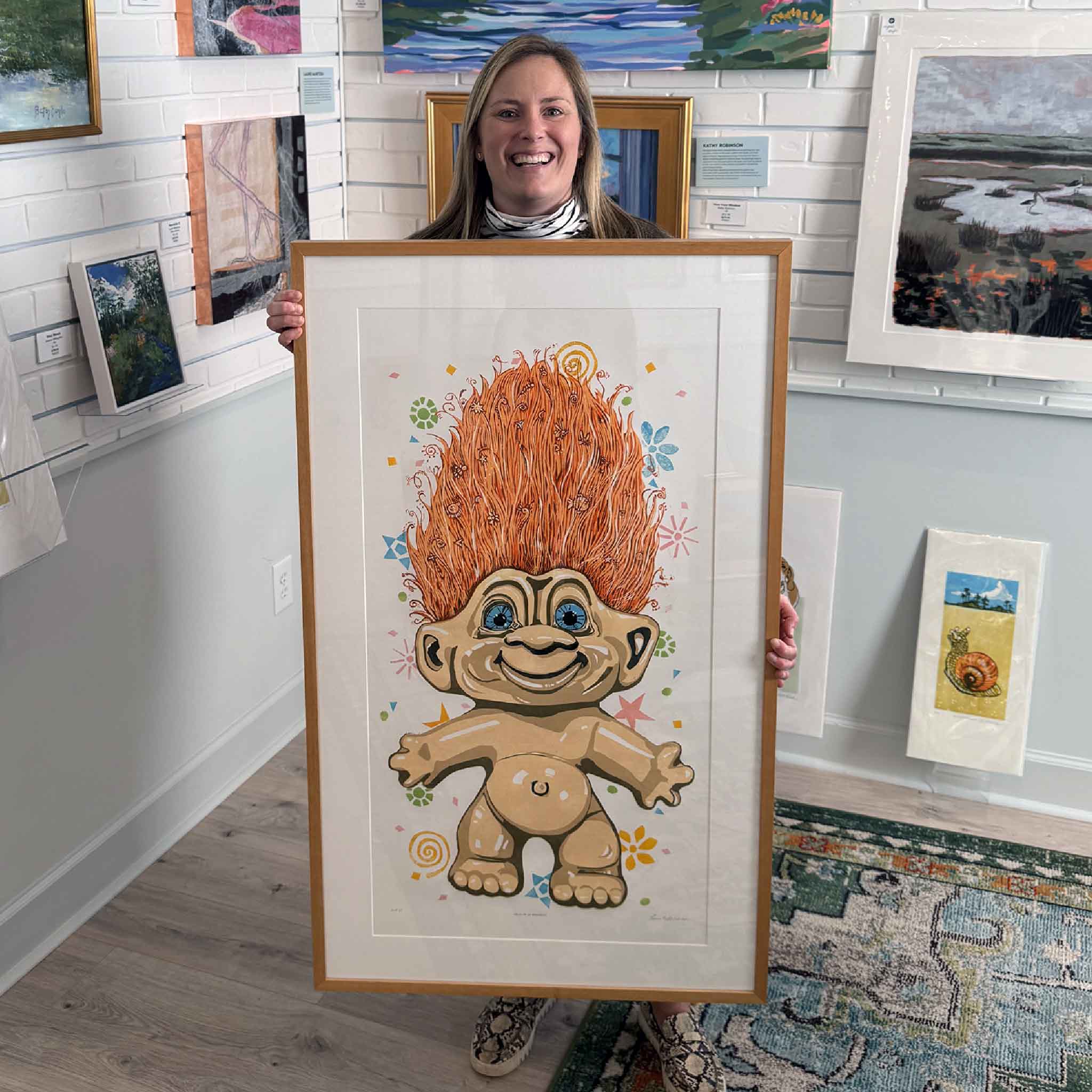 Gray Man Gallery team member Bordy holding Hair Up by local artist Laurie McIntosh to show scale, a large original linocut relief print of a vintage troll photographed inside Gray Man Gallery.