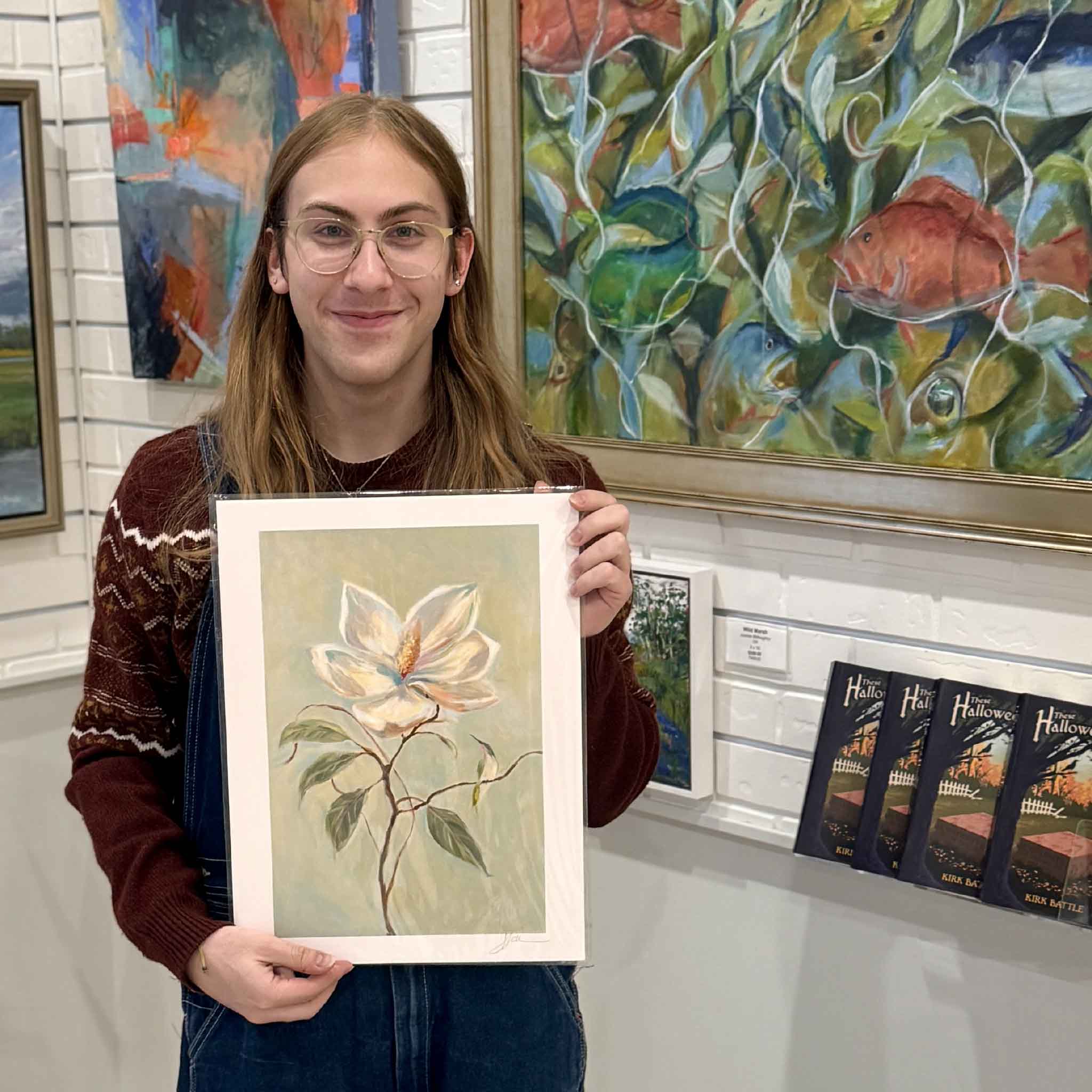 A gallery staff member holds Helli Luck’s Southern Charm 12x16 magnolia print, showing the artwork’s delicate petals and elegant Southern palette.