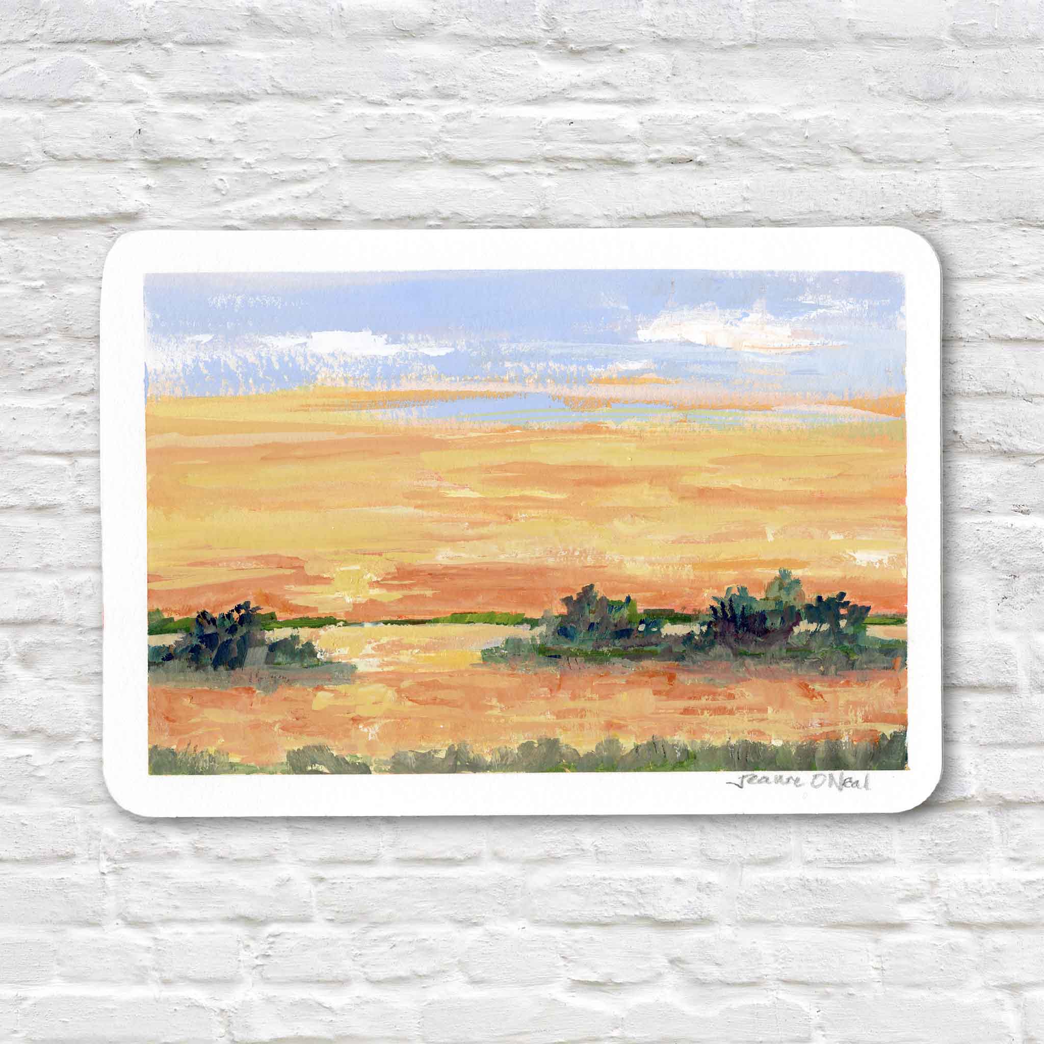 Island Glow by Jeanne O’Neal original gouache coastal sunset painting on postcard featuring warm golden horizon, soft blue sky, and low island silhouettes over reflective water at Gray Man Gallery Pawleys Island