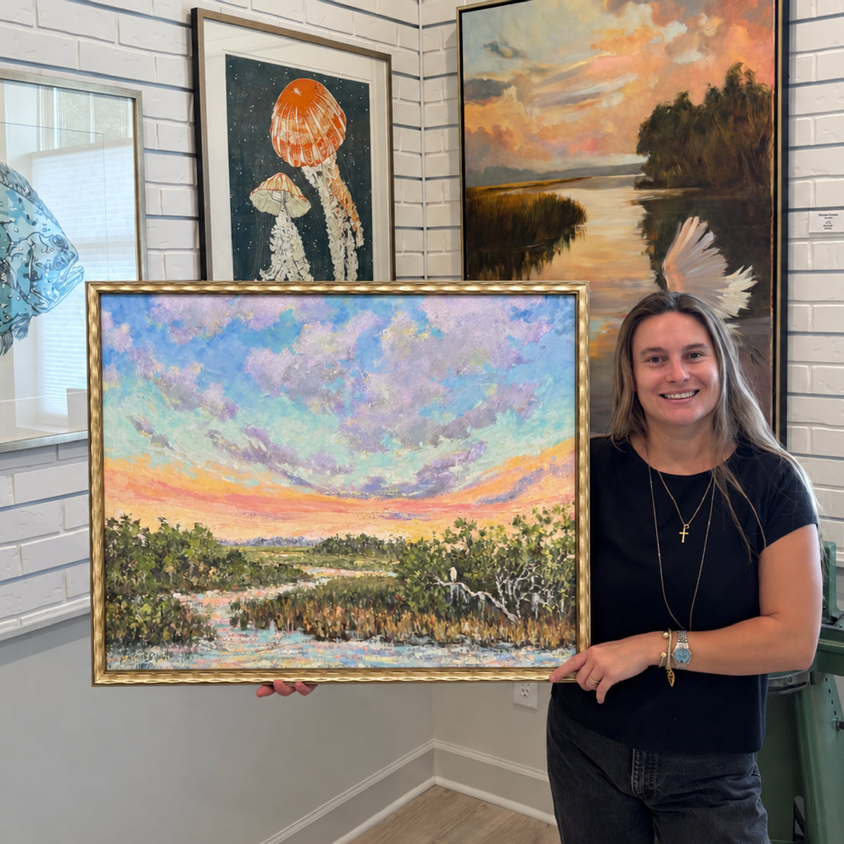 Jeanne O’Neal’s framed original oil painting Joyful Solitude shown inside Gray Man Gallery in Pawleys Island, South Carolina, featuring a colorful Lowcountry marsh landscape with tidal water, coastal grasses and a luminous pastel sunset sky
