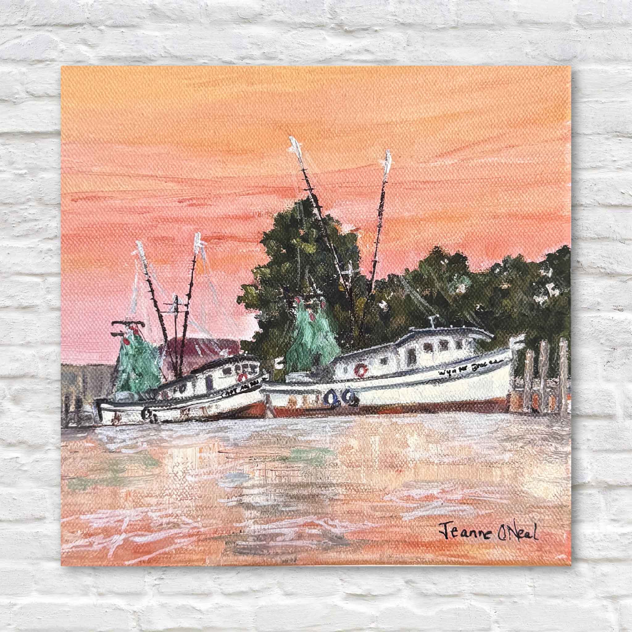 8x8 coastal print of shrimp boats at sunset by Lowcountry artist Jeanne O’Neal, styled against a white brick wall at Gray Man Gallery.