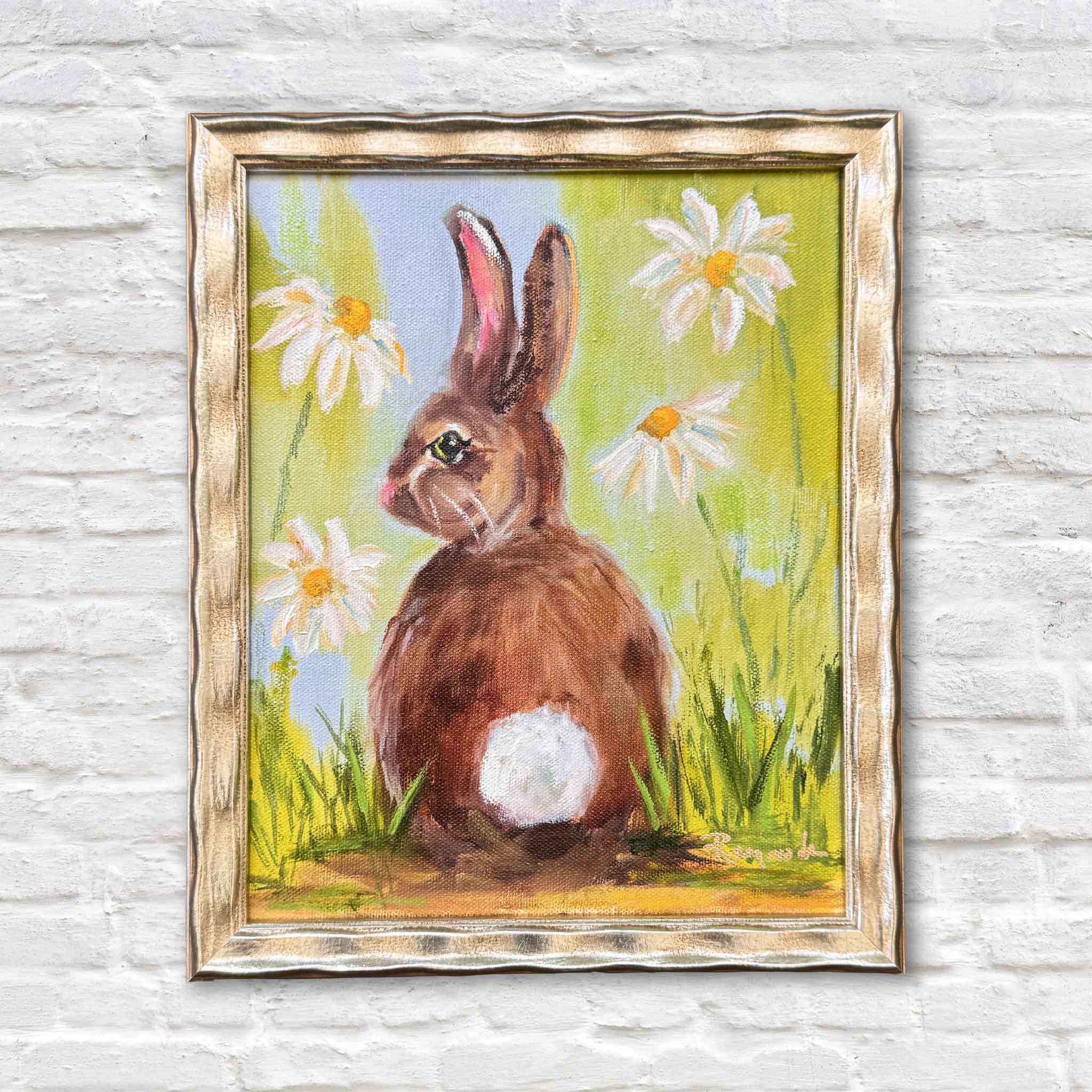Spring Forward by Jenny Reynolds original oil painting featuring a brown bunny sitting among white daisies with yellow centers, set against a bright green and blue spring background, painted in a loose expressive style and presented in the artist’s signature frame at Gray Man Gallery in Pawleys Island, South Carolina