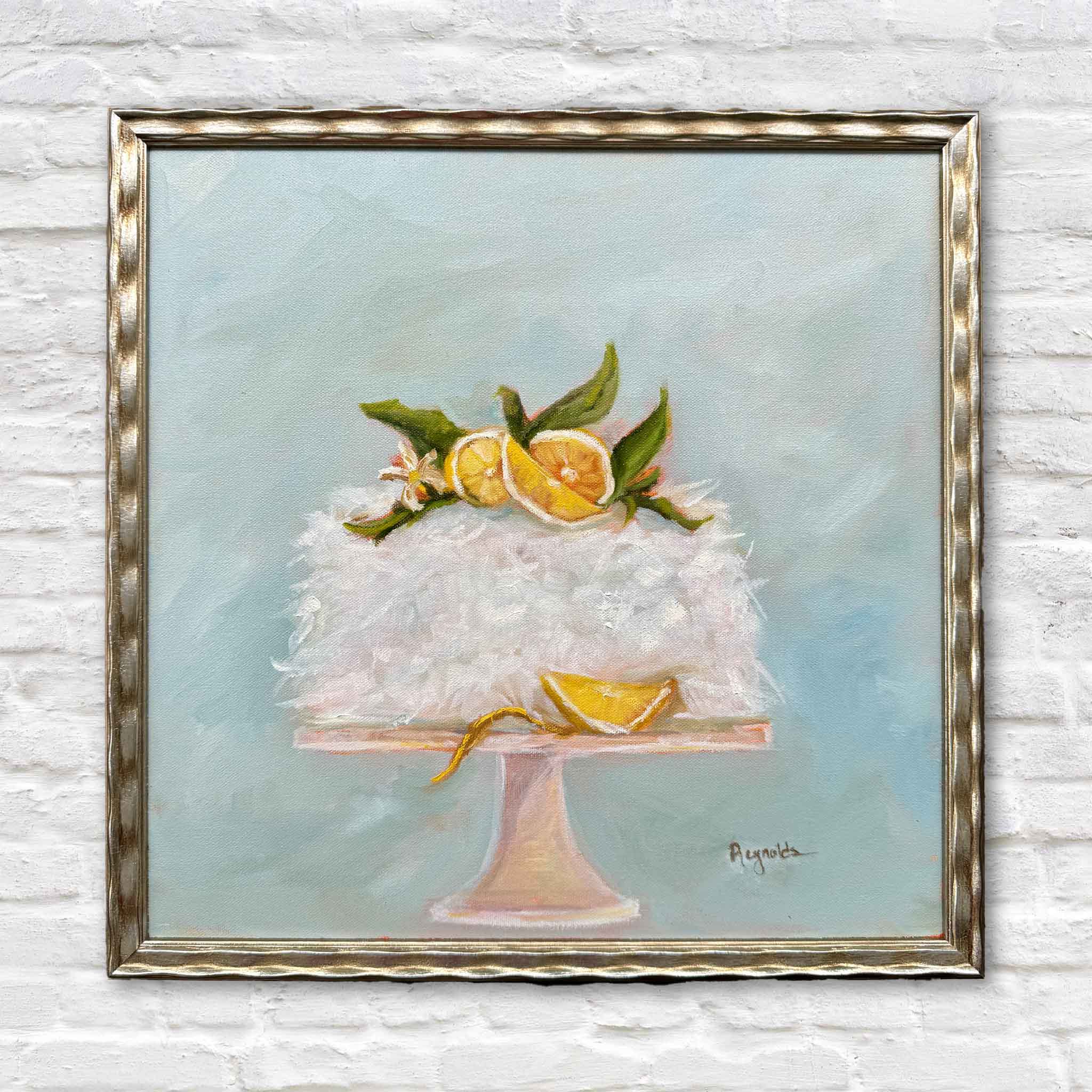 Station 22 Coconut Cake (Secret Recipe!) by local artist Jenny Reynolds is an original oil painting featuring a fluffy coconut cake topped with citrus slices and greenery, framed in the artist’s signature champagne frame at Gray Man Gallery in Pawleys Island