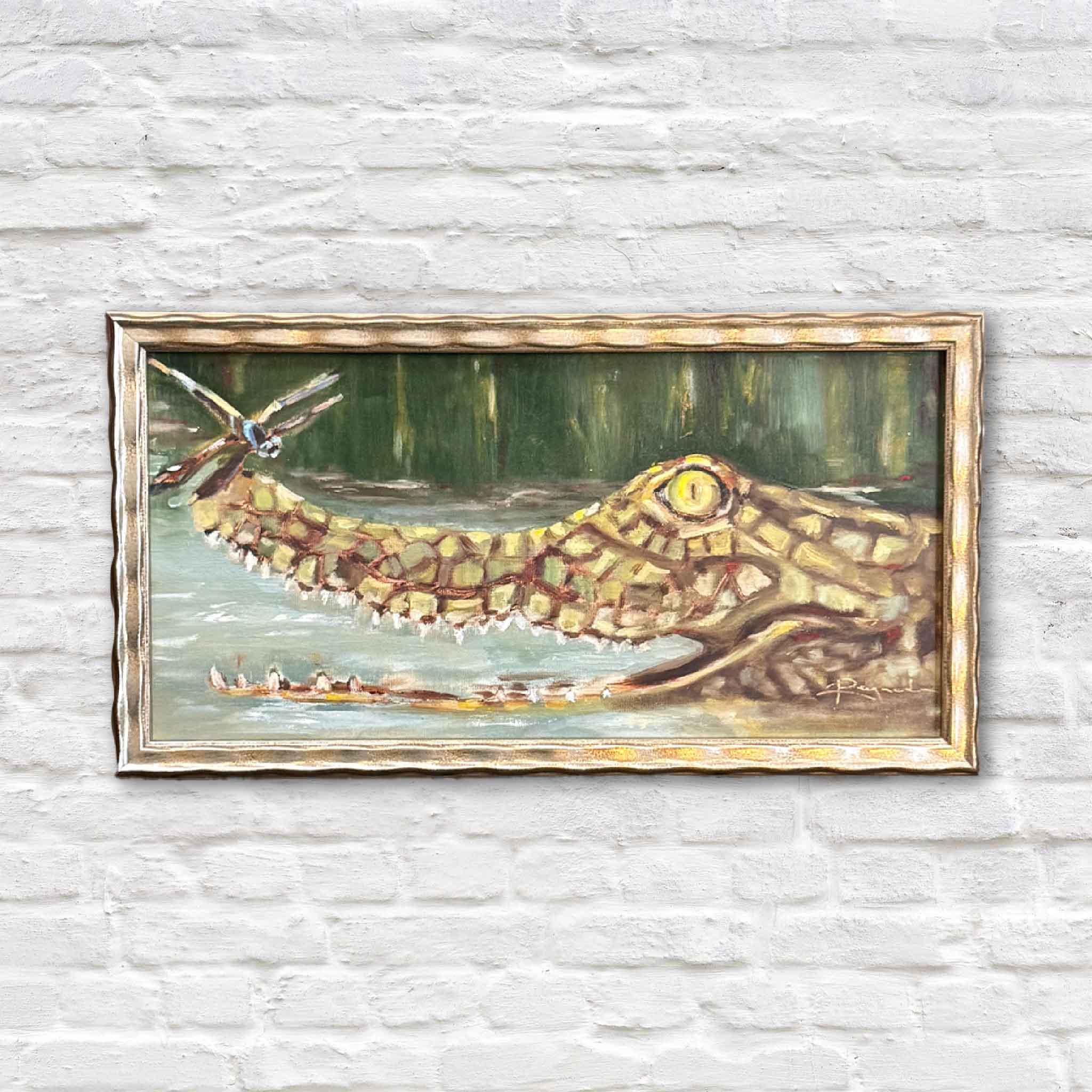 A framed original oil painting by Jenny Reynolds showing a whimsical marsh gator gliding through green water with reeds in the background.