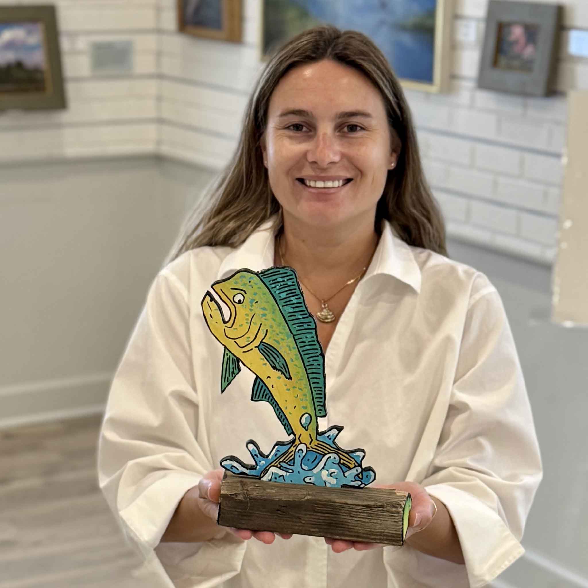 Kyra displays Mahi Mahi Mahi Mahi, an original mixed media sculpture by Charleston artist Nick Kawczynski. Hand-painted on reclaimed marine-grade plywood salvaged through the Lowcountry Maritime Society's youth boatbuilding program, this colorful mahi-mahi sculpture is available exclusively at Gray Man Gallery in Pawleys Island, South Carolina.