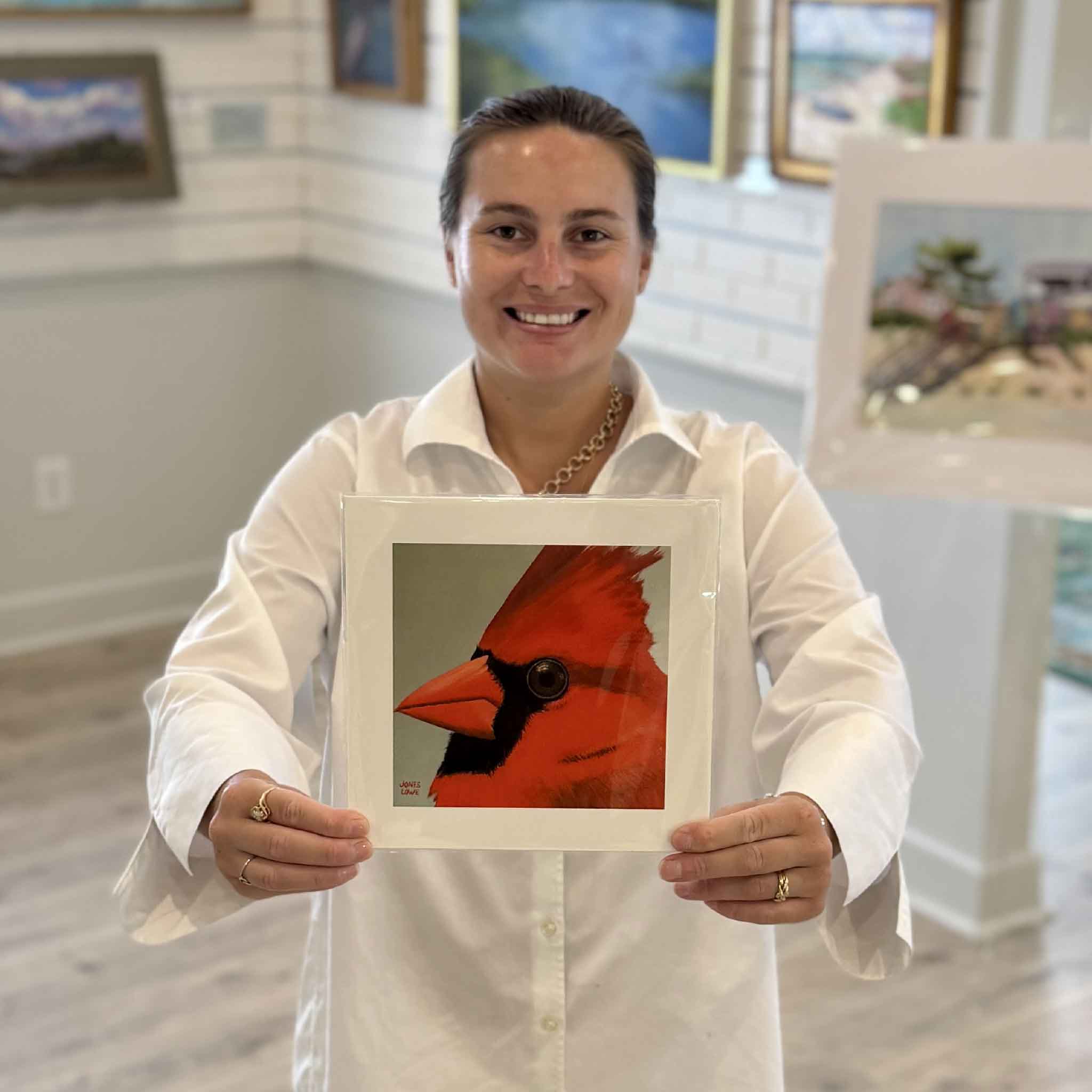Kyra holds Northern Cardinal II, an 8×8 bird print by Georgetown local artist Nancy Jones Lowe at Gray Man Gallery in Pawleys Island. Printed on premium 100% cotton archival fine art paper with archival pigment inks, this colorful cardinal portrait fits any standard 8×8 frame without custom framing.