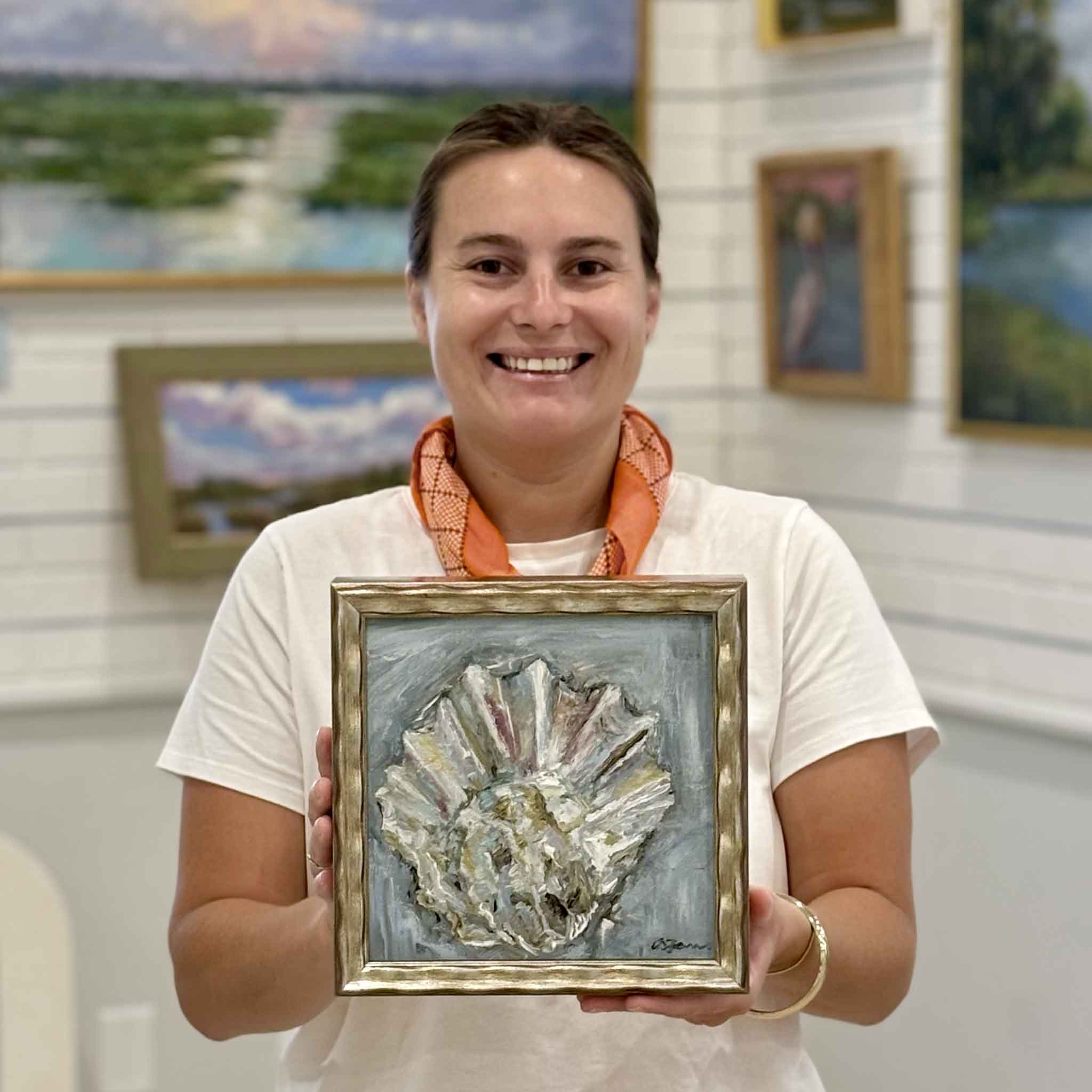 Kyra holding Reverie by local South Carolina artist Allison Farr to show scale, an original framed oyster oil painting from the Lowcountry Jewels collection at Gray Man Gallery in Pawleys Island, South Carolina.