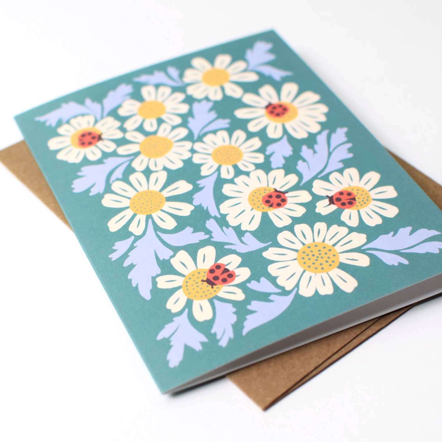 Open view of the Ladybugs & Chamomile greeting card by Chrissie Van Hoever displayed with its recycled kraft envelope, highlighting the premium recycled cardstock and botanical illustration available at Gray Man Gallery in Pawleys Island, South Carolina.