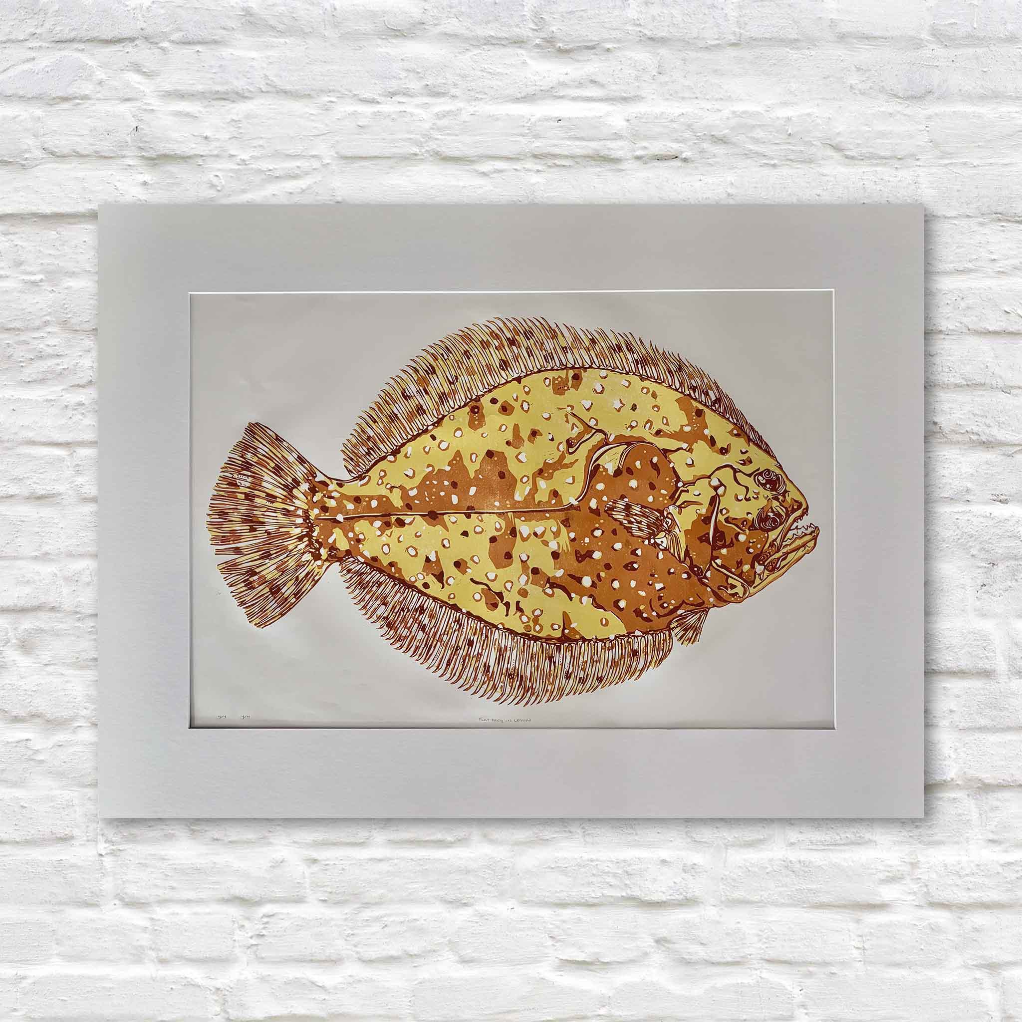 Original signed reduction linocut titled Flat Fred in Lemon by Laurie Brownell McIntosh, featuring a golden yellow flounder hand printed in layered ochre, amber, and warm brown inks. This professionally matted 30x40 Lowcountry print is available at Gray Man Gallery in Pawleys Island, South Carolina.