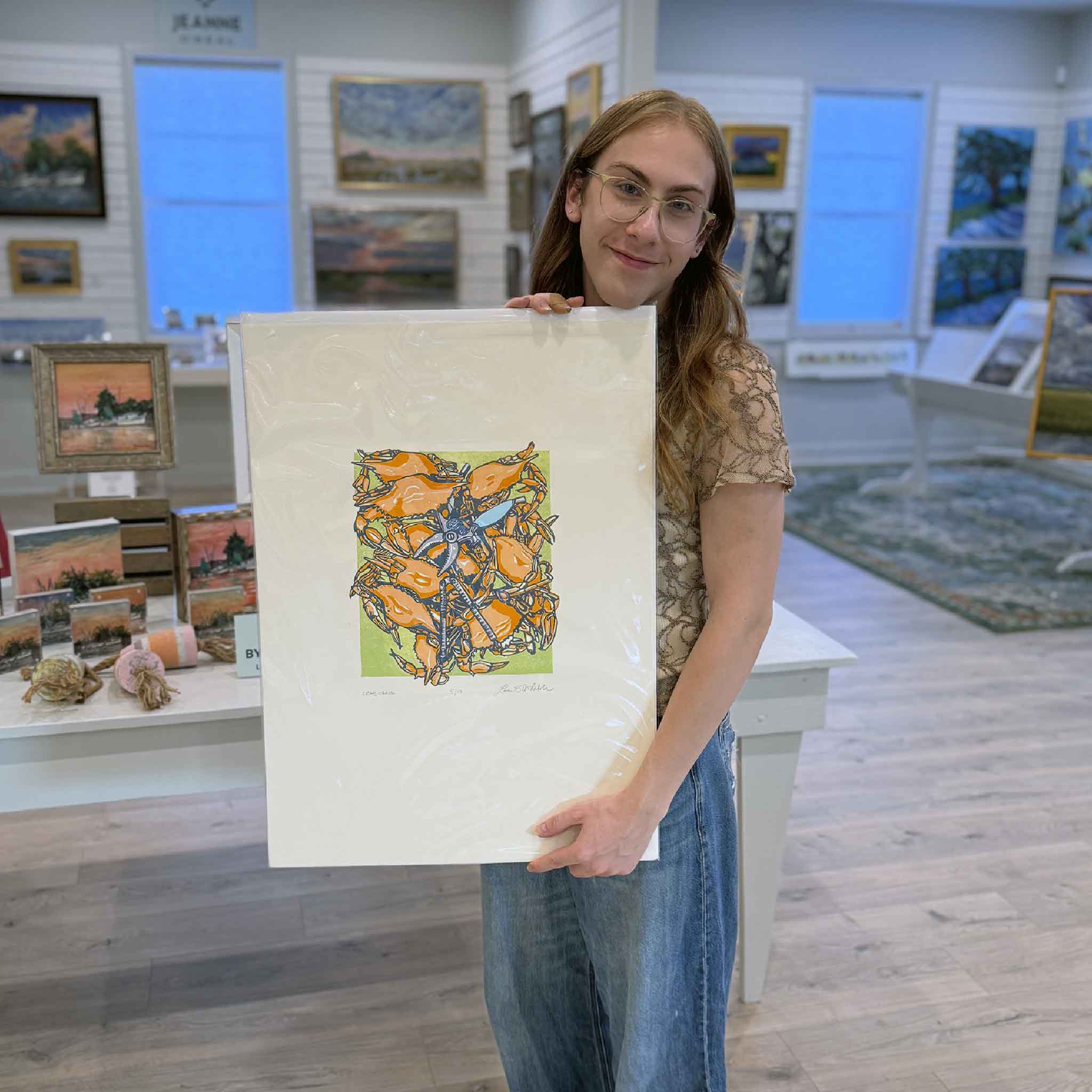 Original linocut “Crab Crack” by Laurie McIntosh held at Gray Man Gallery, featuring a lively cluster of orange crabs surrounding crossed crab crackers.