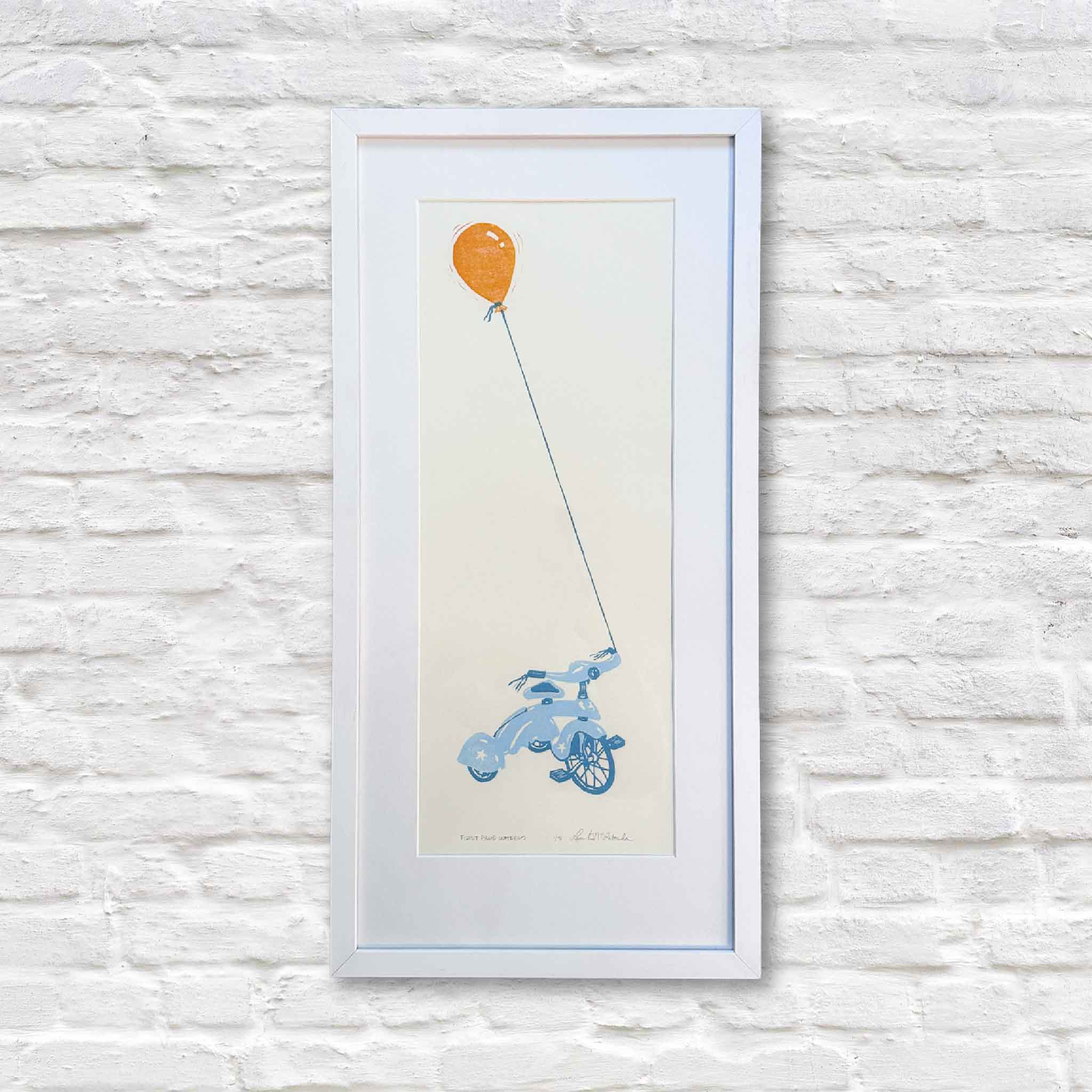 Original First Blue Wheels linocut by Laurie McIntosh featuring a blue tricycle tethered to a floating orange balloon, professionally framed and displayed at Gray Man Gallery in Pawleys Island, South Carolina.