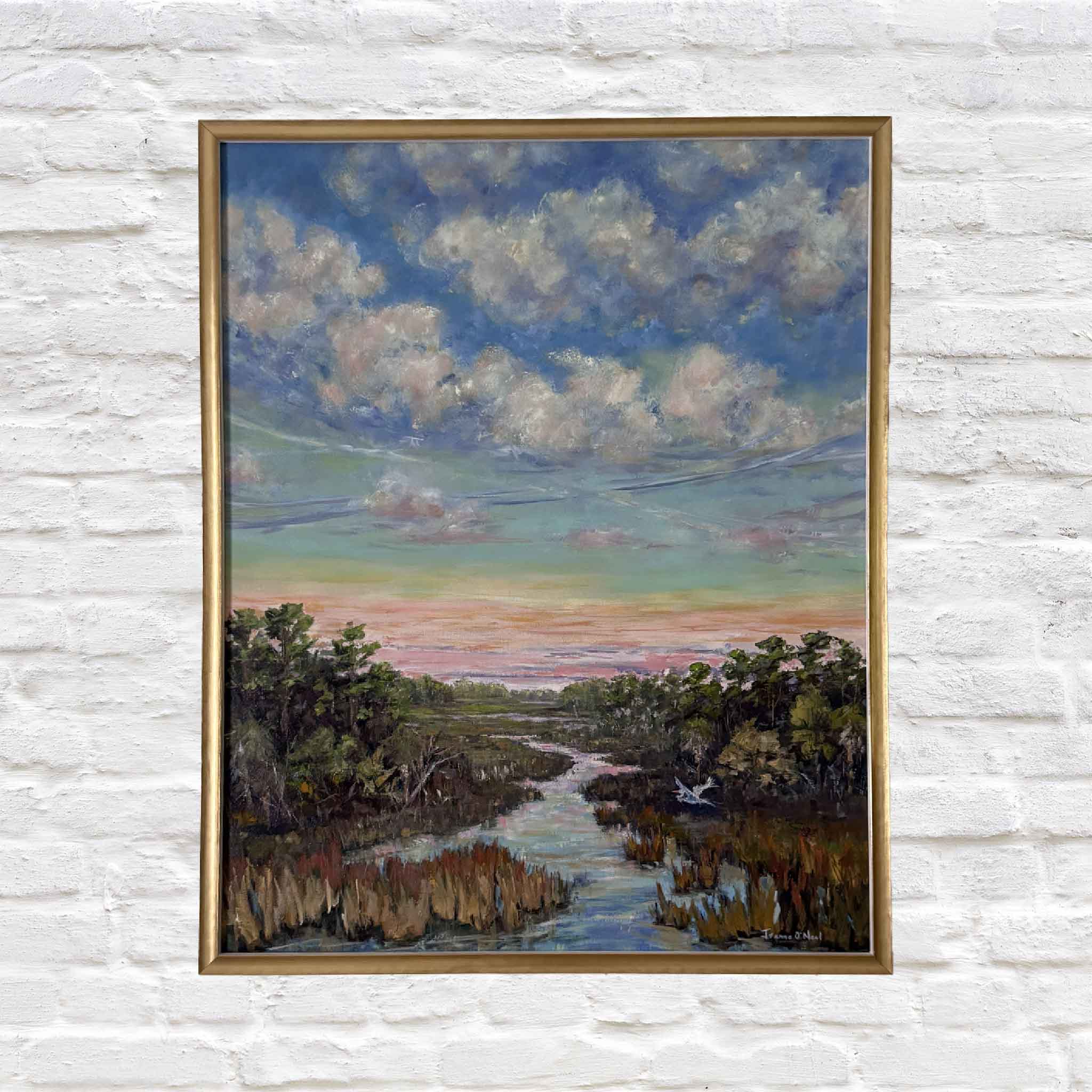 Framed painting of a landscape with a river and trees on a white brick wall.