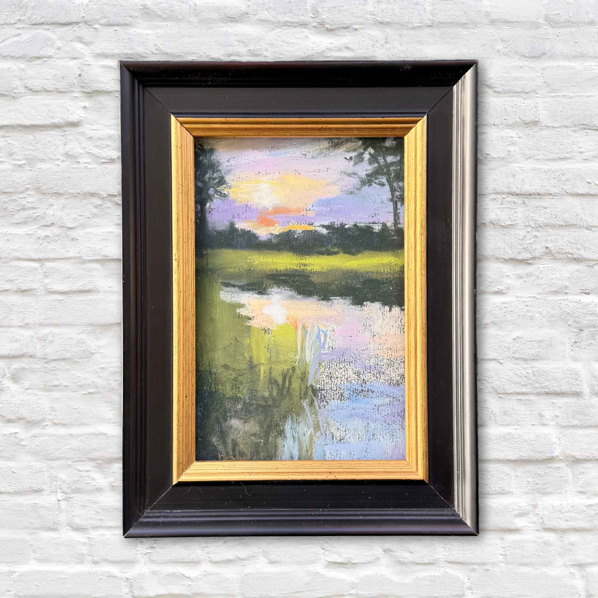 Marsh Sunset is an original framed pastel by Lowcountry artist Joanne Willoughby, depicting a serene coastal marsh at dusk with reflective water and a glowing pastel sky.