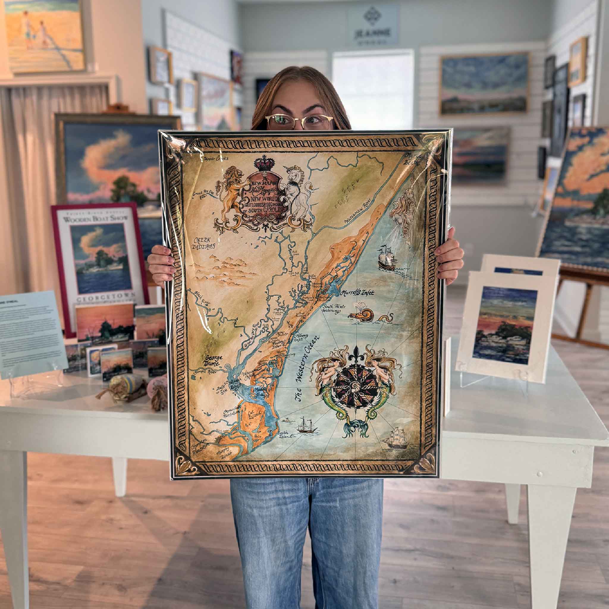 Large Mermaids & Marshlands Lowcountry map print held for scale inside Gray Man Gallery.