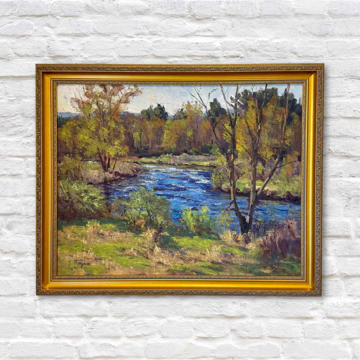 Quiet Bend of the River original oil painting by artist Michael Rogan featuring vivid blue water winding through a wooded river landscape with green and golden foliage, presented in an ornate gold frame at Gray Man Gallery in Pawleys Island, South Carolina