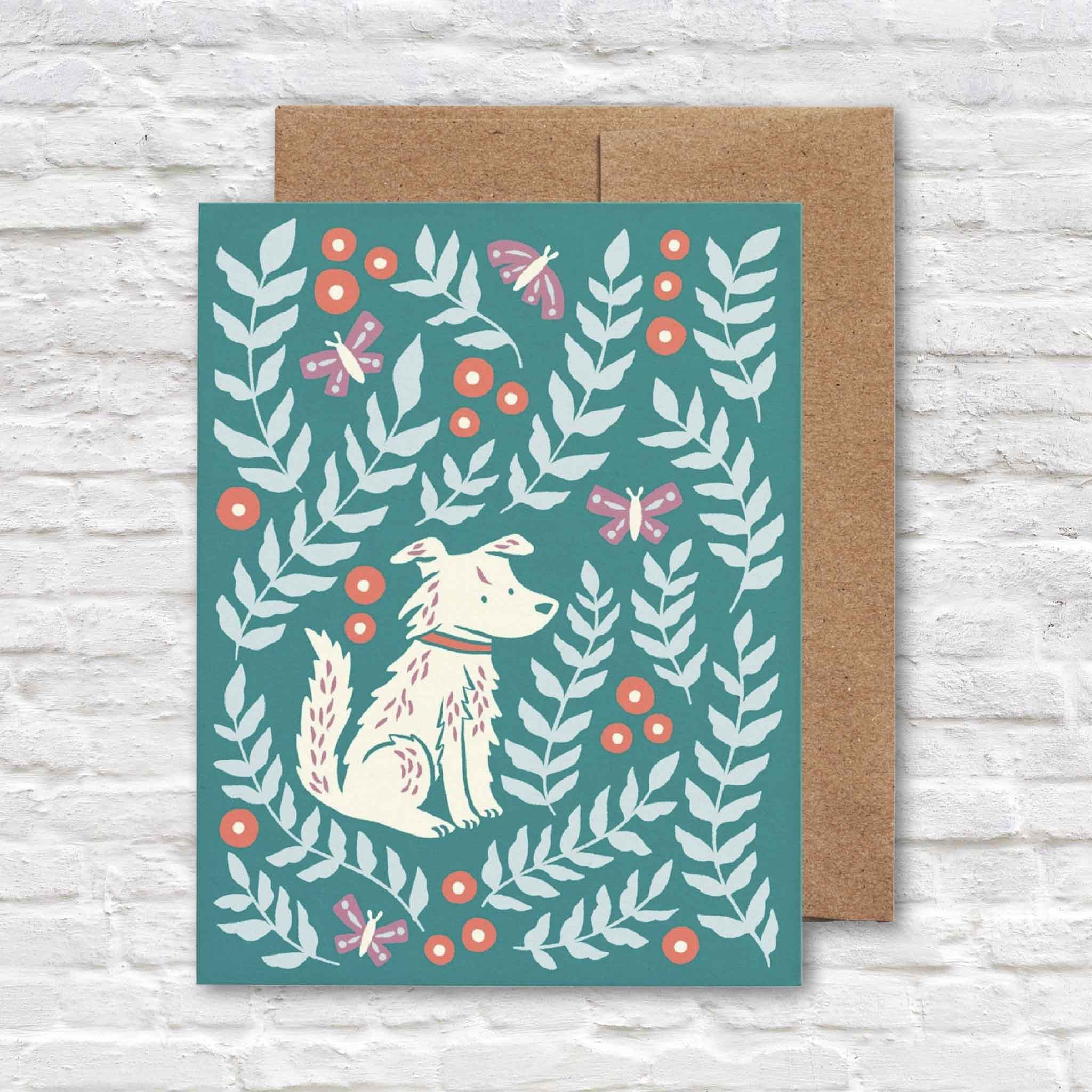 Molly Meadows greeting card by Chrissie Van Hoever featuring an illustrated white dog surrounded by leafy botanical branches, butterflies, and berries with a recycled kraft envelope. Available at Gray Man Gallery in Pawleys Island, South Carolina.
