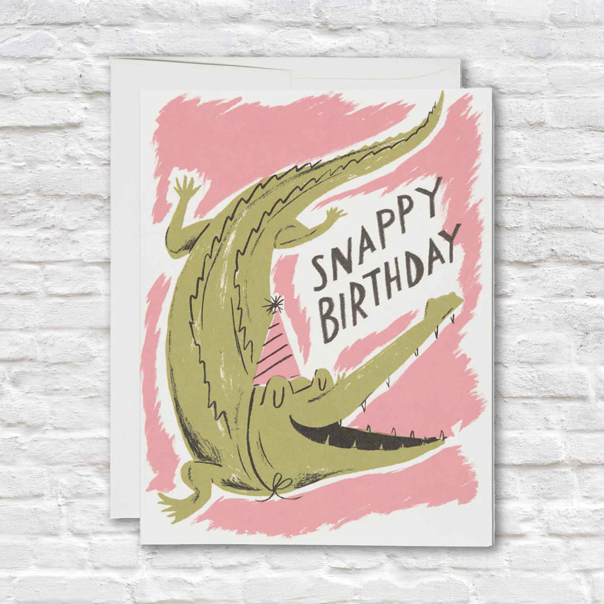 Snappy Birthday alligator greeting card illustrated by Nicholas John Frith for Red Cap Cards featuring a playful crocodile wearing a party hat with a fun birthday pun. Shop this blank-inside birthday card at Gray Man Gallery in Pawleys Island, South Carolina.