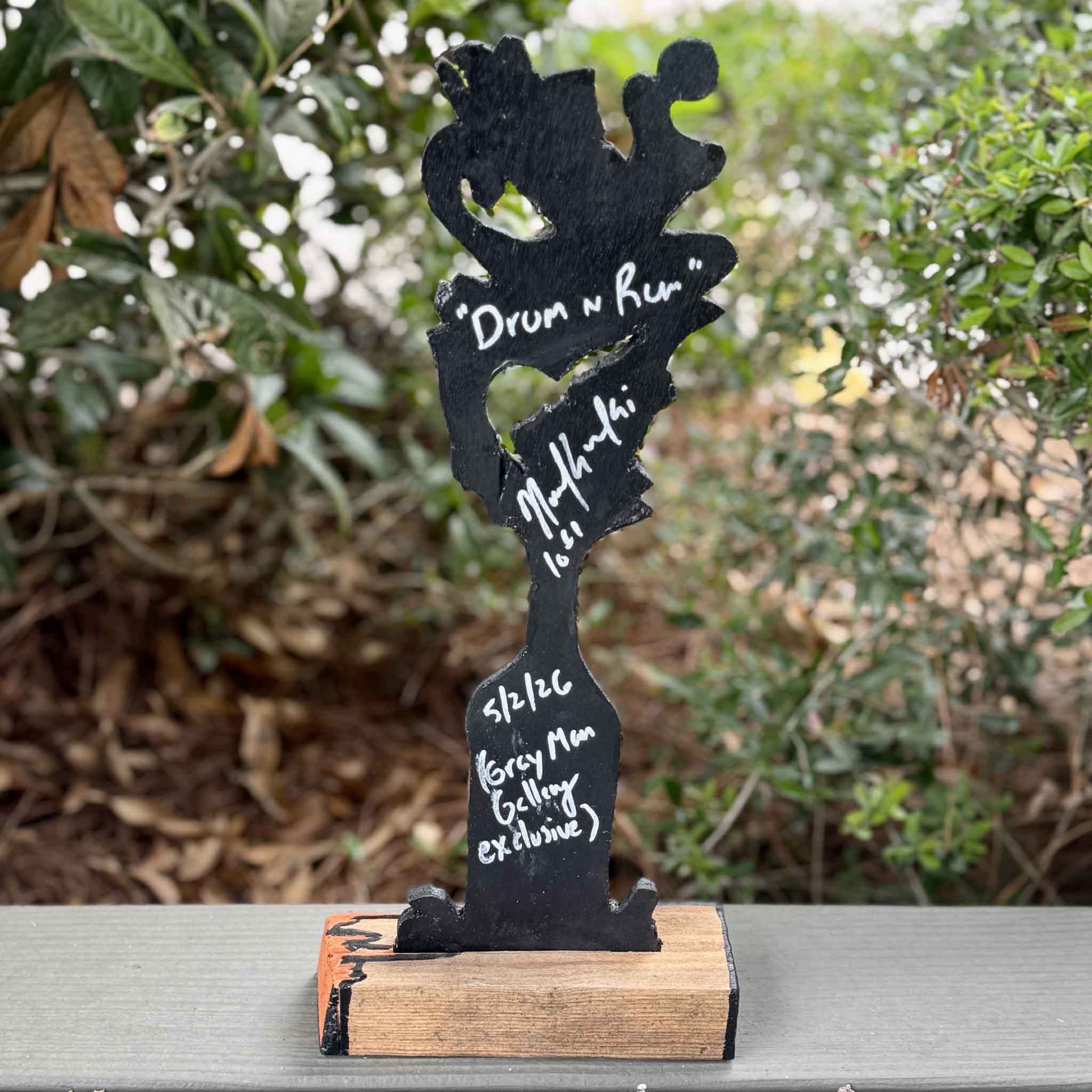 Back view of Drum 'n Rum by Charleston artist Nick Kawczynski showing the artist's signature, title, date, and Gray Man Gallery exclusive inscription. The sculpture is handcrafted from reclaimed marine-grade plywood salvaged through the Lowcountry Maritime Society's educational boatbuilding program in South Carolina.