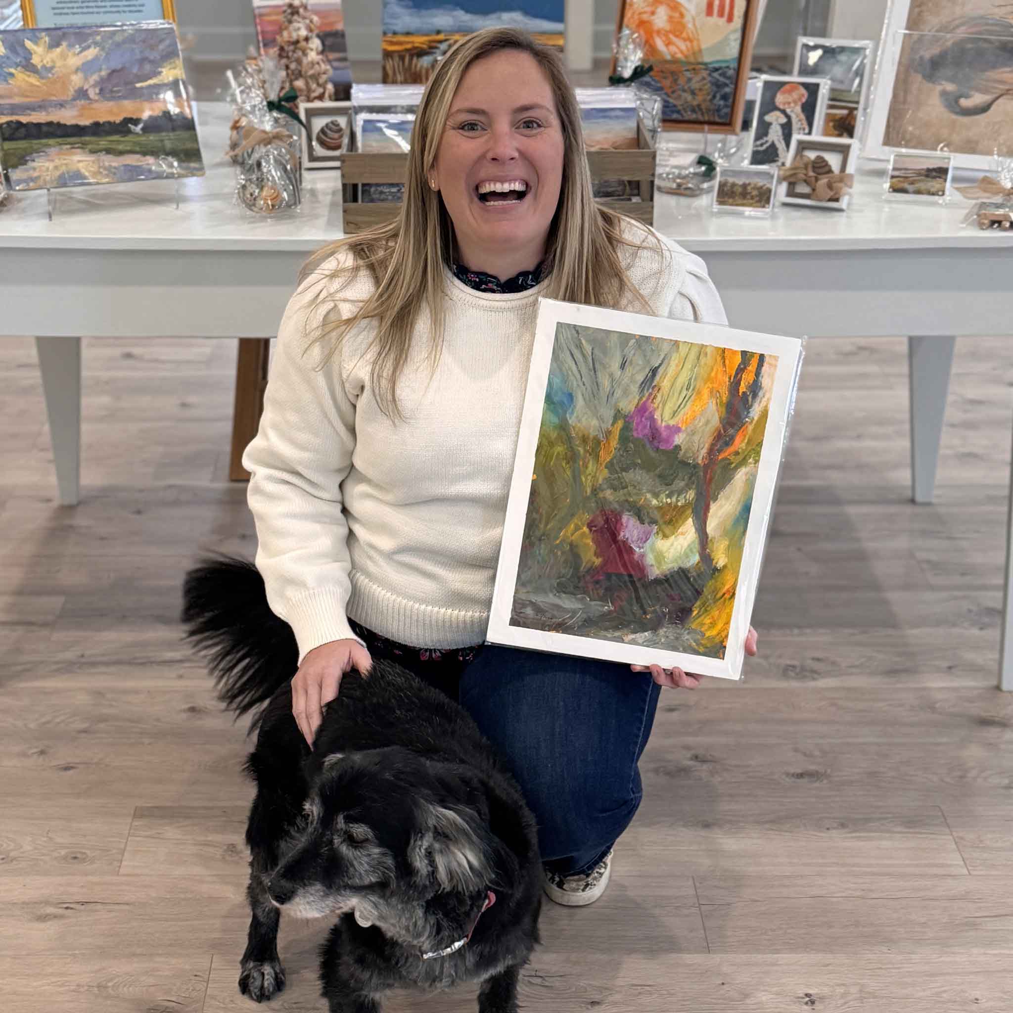 Gray Man Gallery team member holding local artist Caroline Young's original mixed media artwork Night Garden inside Gray Man Gallery in Pawleys Island, South Carolina, showing scale and texture of the contemporary abstract painting.