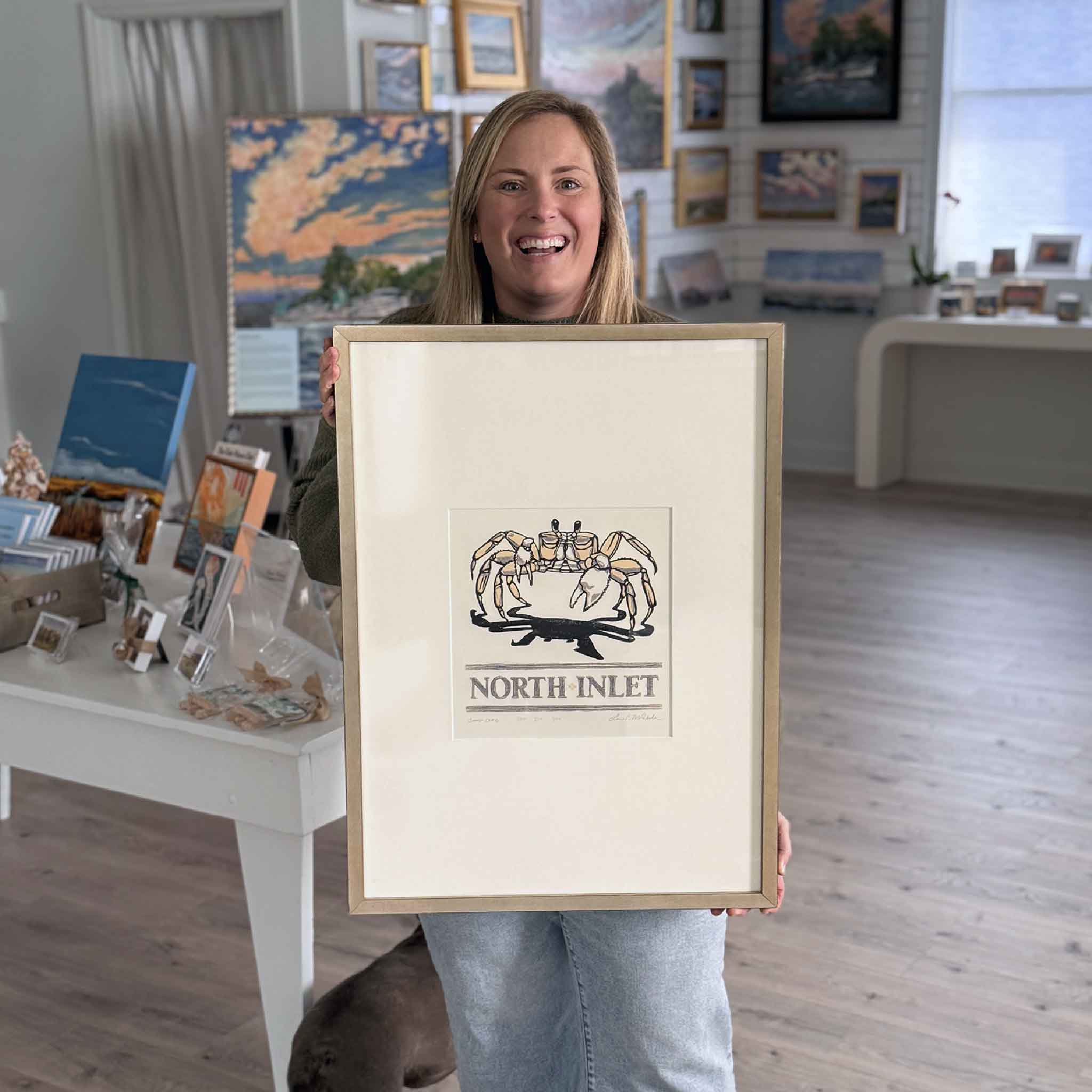 Bordy from Gray Man Gallery holding North Inlet: Ghost Crab by local artist Laurie McIntosh to show scale inside the gallery.