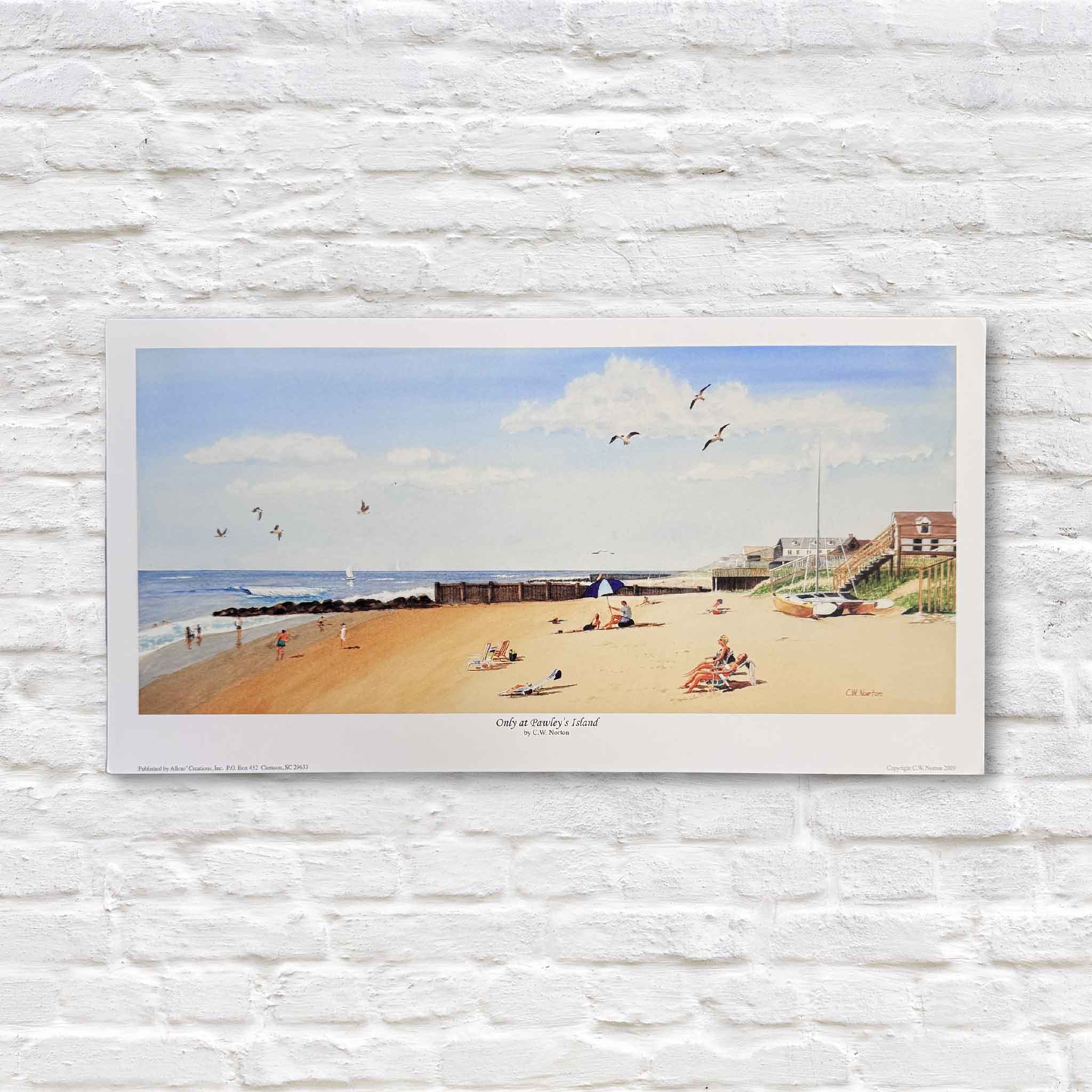 A detailed watercolor print by C.W. Norton depicting a sunny day on Pawleys Island, with beachgoers lounging on the sand, seabirds flying overhead, gentle surf, and classic coastal cottages lining the shoreline.