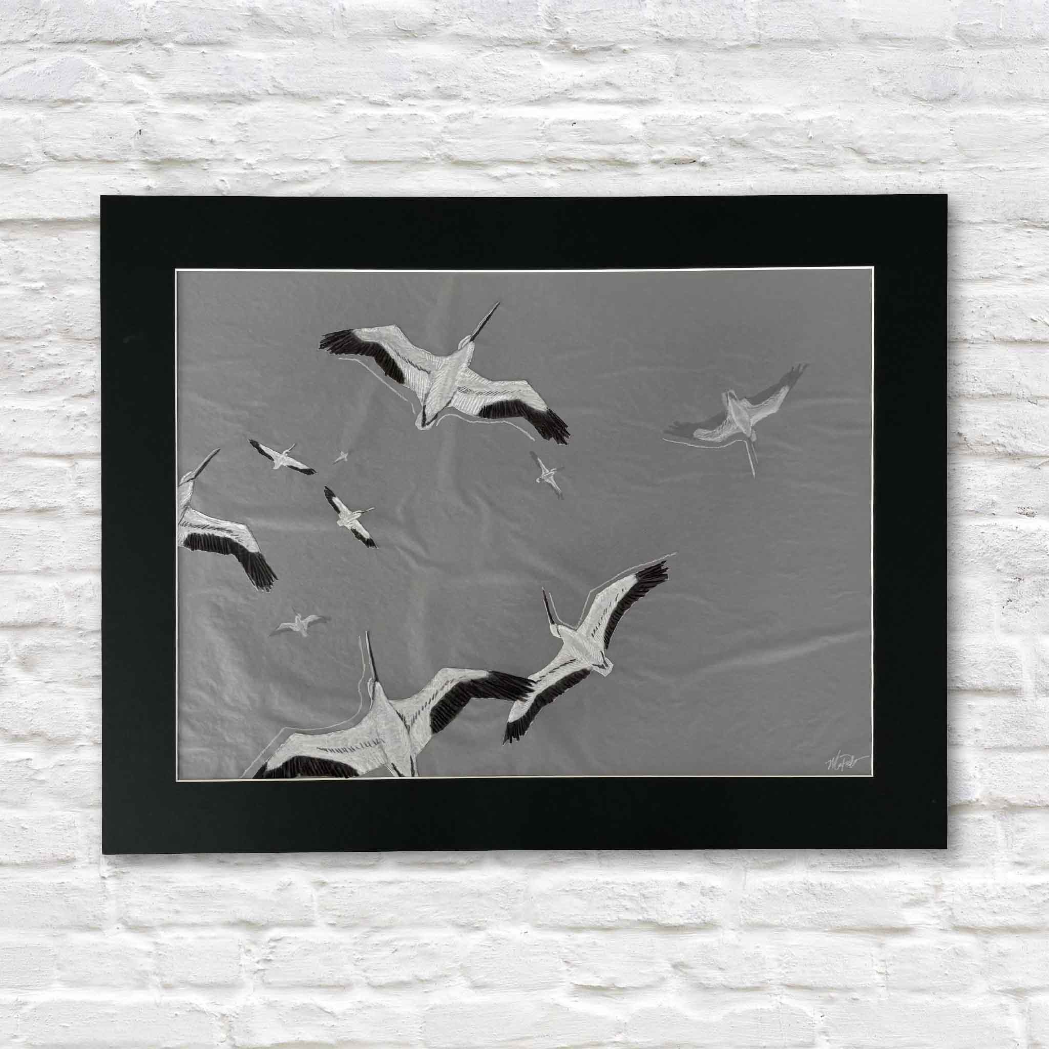 Original mixed-media artwork, Passing Through, by South Carolina artist Maggie Pelton, featuring a flock of wood storks soaring across a soft gray sky. Built with layered tracing paper, graphite, and ink, this one-of-a-kind original is professionally matted to fit a standard 22x28 frame and available at Gray Man Gallery in Pawleys Island.