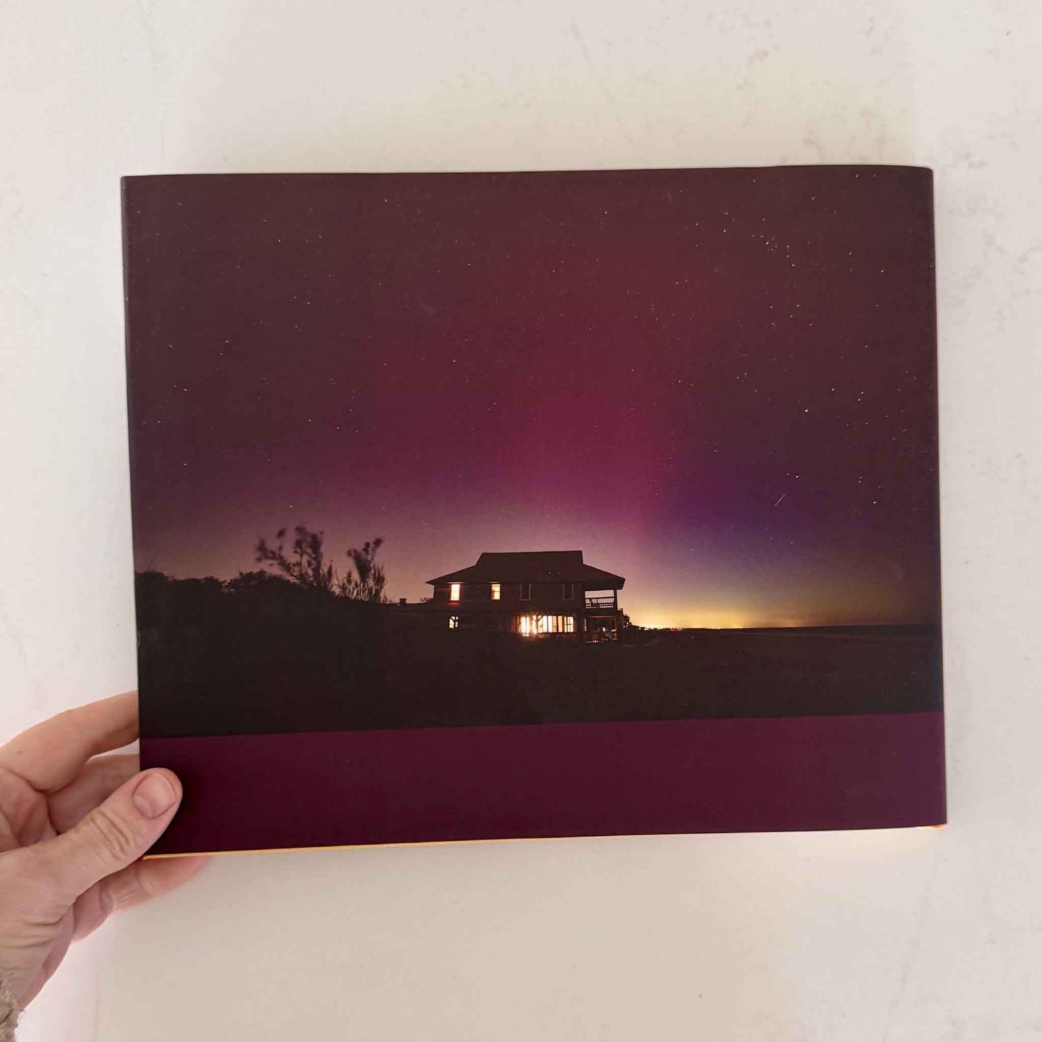 Back cover of Pawleys Island Reflections of Light photography book by local Pawleys Island artist Tanya Ackerman featuring aurora borealis visible above an oceanfront home in Pawleys Island