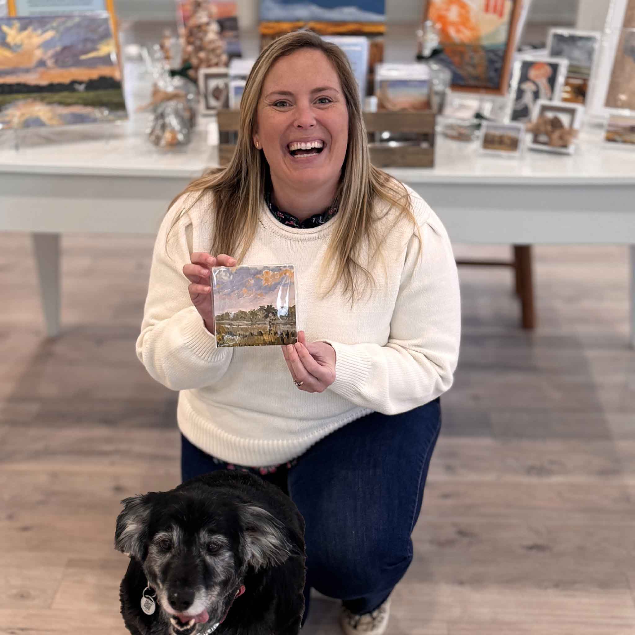 Customer holding Psalm Sunday 5x5 fine art print by local artist Jeanne O’Neal inside Gray Man Gallery, showing scale and presentation of the coastal marsh artwork in a Pawleys Island gallery setting