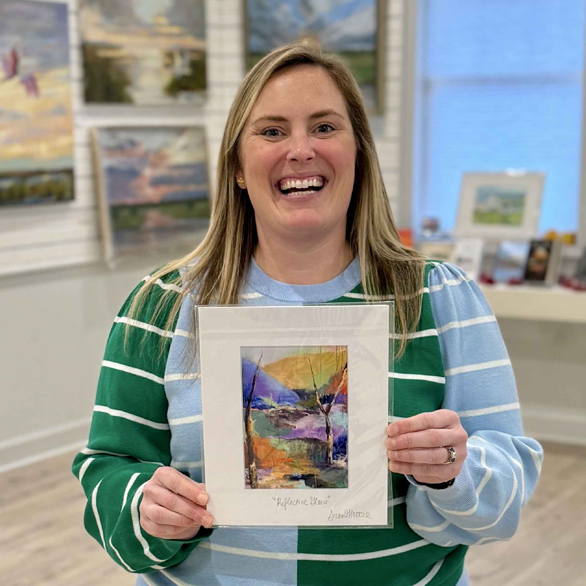 Gray Man Gallery staff member holding Reflective Glow fine art giclée print by local artist Susan Moore inside Pawleys Island gallery, showcasing abstract Lowcountry coastal artwork
