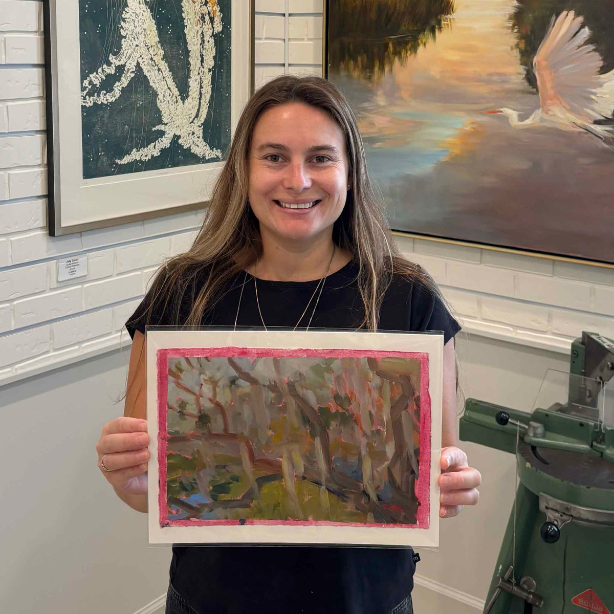 Gray Man Gallery team member holding Coastal Oak #209, an original oil on paper by local artist Retta Dotterer, showing the scale of the expressive Lowcountry live oak painting and its hand-painted pink border.