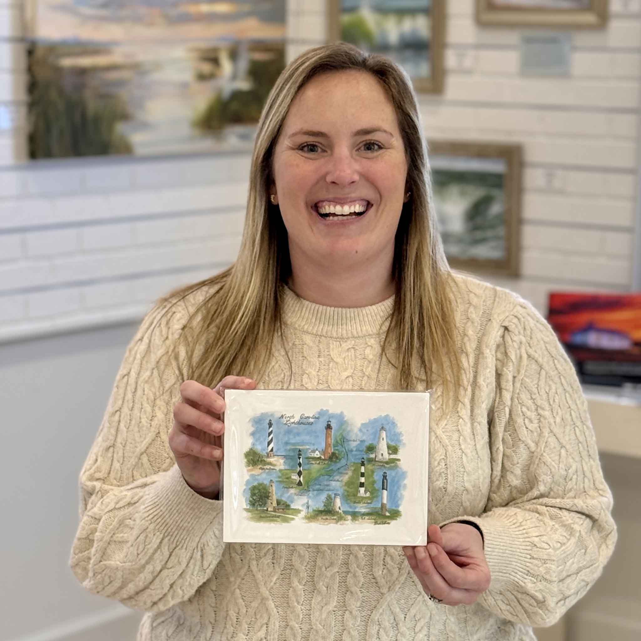 Bordy holding North Carolina Lighthouses watercolor print by coastal artist Ronald Williams featuring Cape Hatteras and Outer Banks beacons at Gray Man Gallery