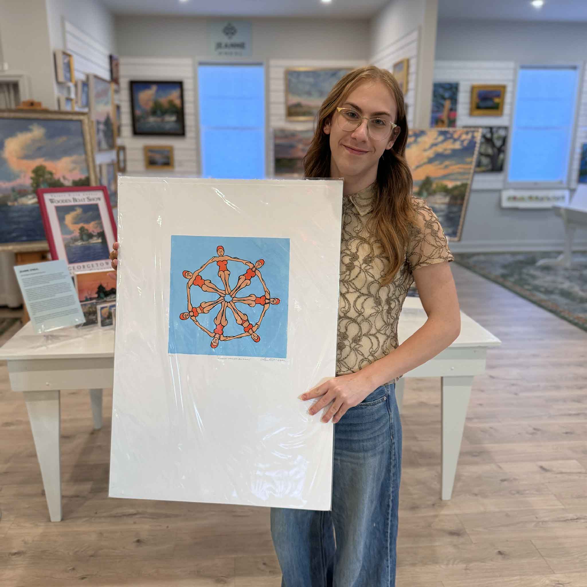 Alex holding the Scarlet Women Swimmin’ linocut print by Laurie McIntosh inside Gray Man Gallery.