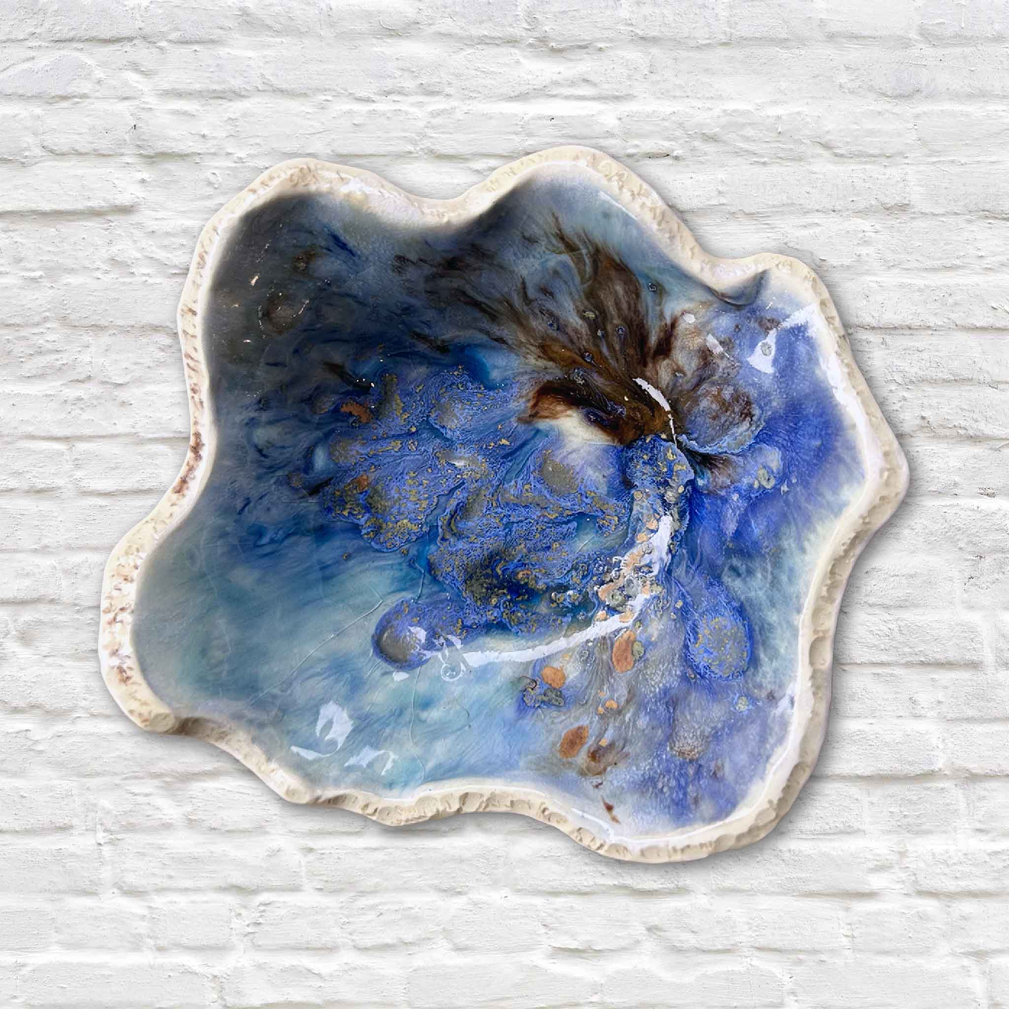 Handmade Seaspray pottery bowl by Vida Miller with blue, cream, and brown glazes and organic wavy edges.
