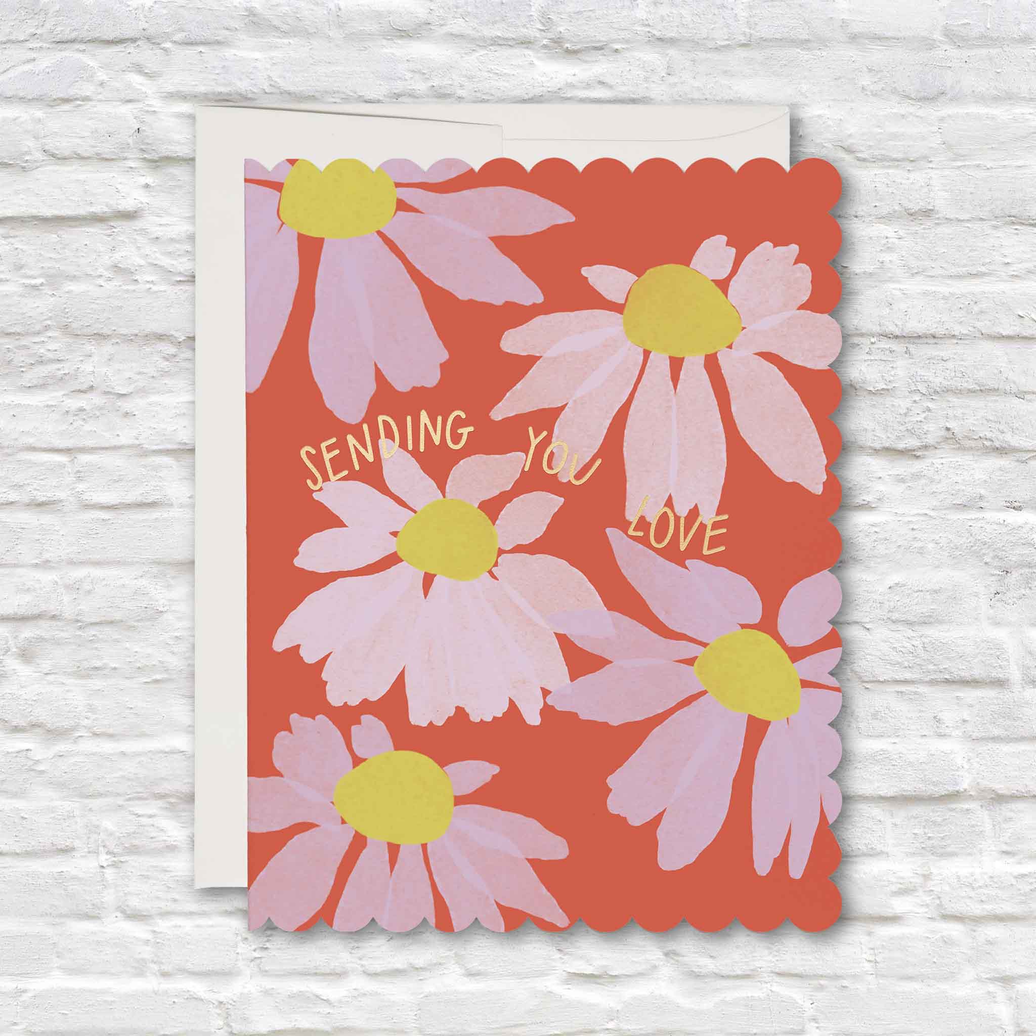 Sending You Love scalloped floral greeting card featuring oversized pink coneflowers with bright yellow centers on a vibrant coral-red background, metallic gold foil lettering and playful die-cut scalloped edges, available at Gray Man Gallery in Pawleys Island, South Carolina.