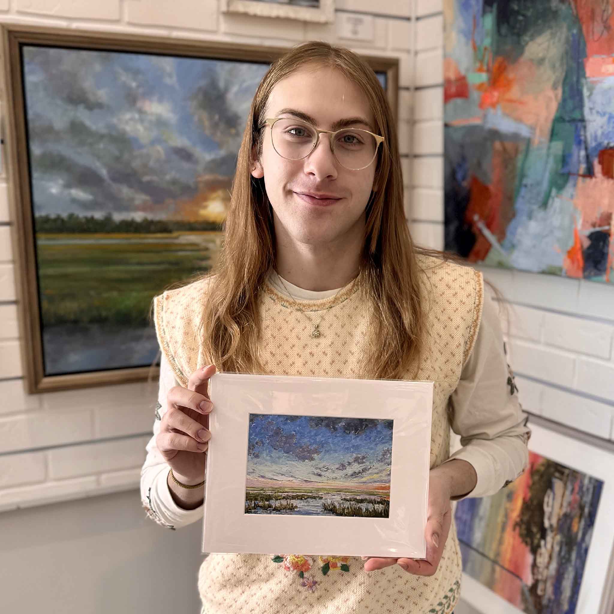 A Gray Man Gallery team member holds Symphony, an 8 × 10 matted fine art giclée by Jeanne O’Neal, showing its size, presentation, and gift-ready scale.