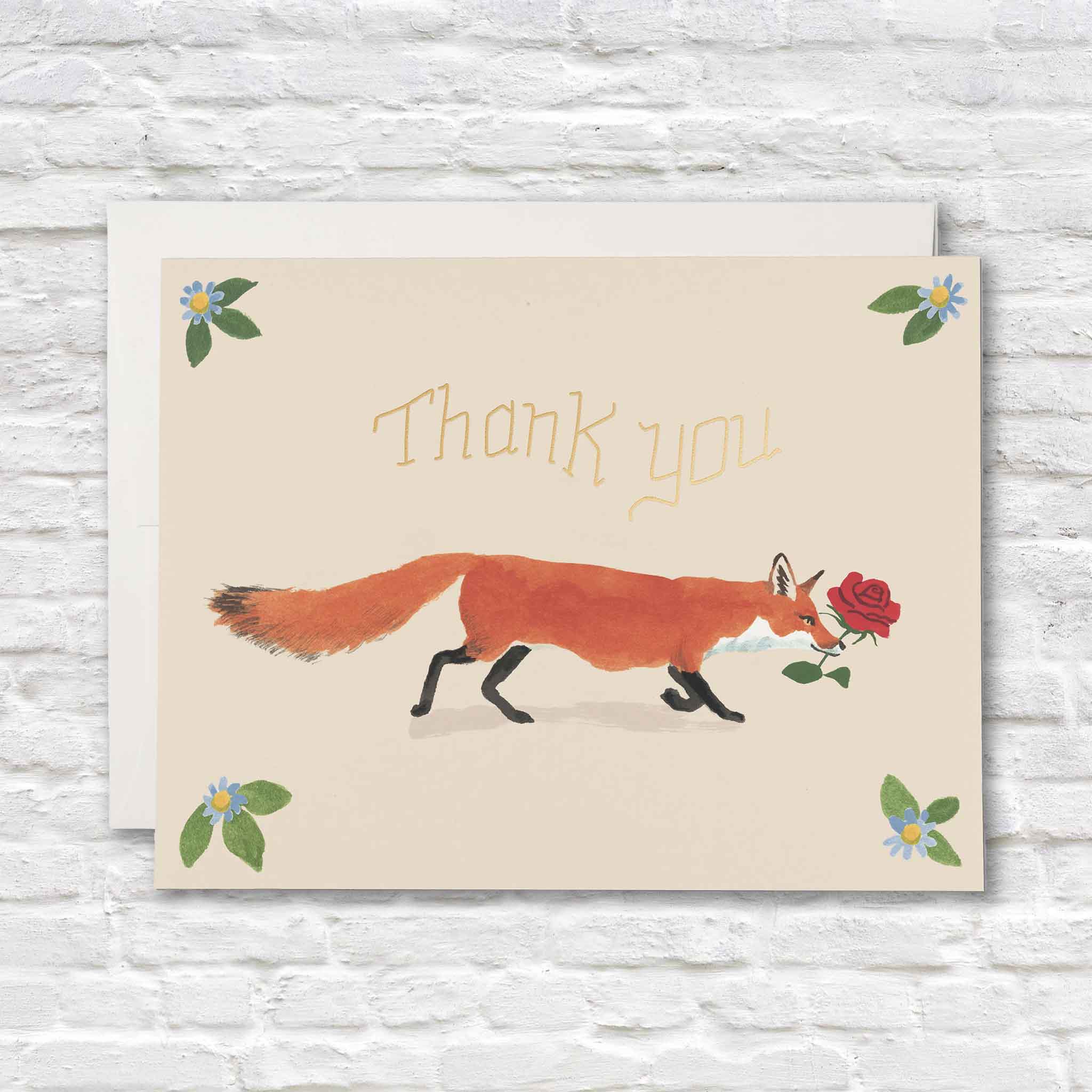 Thank You Fox greeting card illustrated by Danielle Kroll featuring a graceful red fox carrying a single red rose beneath elegant gold foil "Thank You" lettering with delicate blue wildflowers in each corner. This Red Cap Cards thank-you card is blank inside and available at Gray Man Gallery in Pawleys Island, South Carolina, making it a beautiful choice for expressing appreciation after weddings, birthdays, showers, dinners, gifts, or everyday acts of kindness.